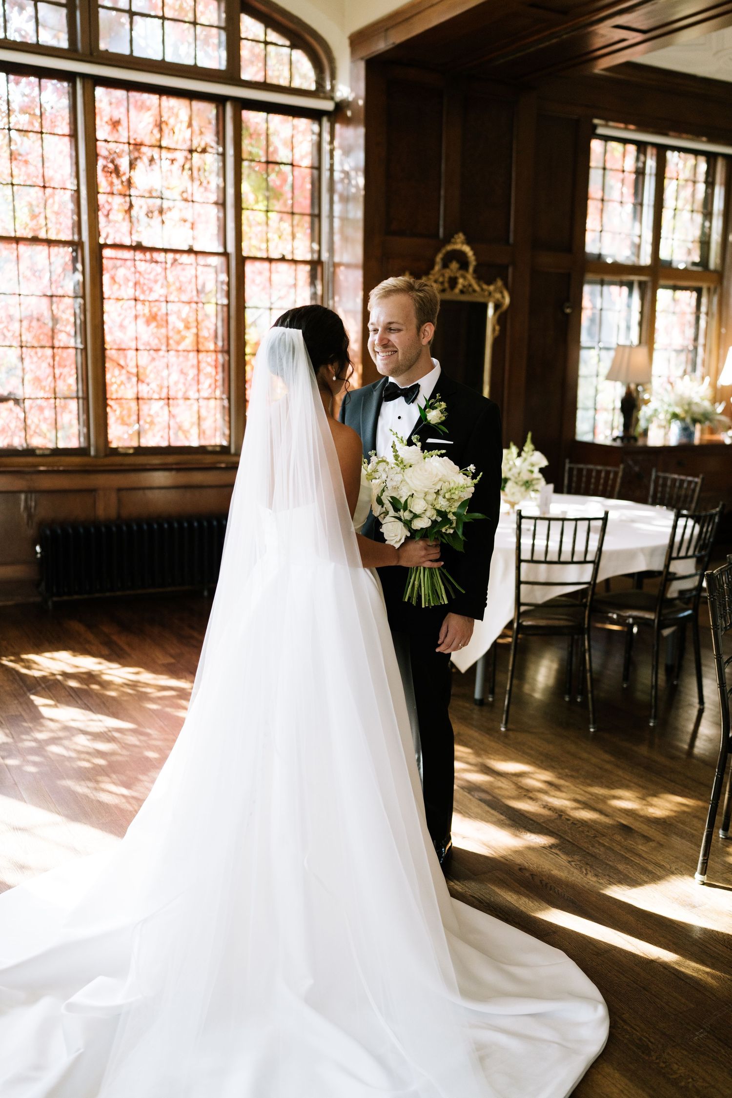 Sunlit wedding photo of a couple in an elegant room with arched windows.
