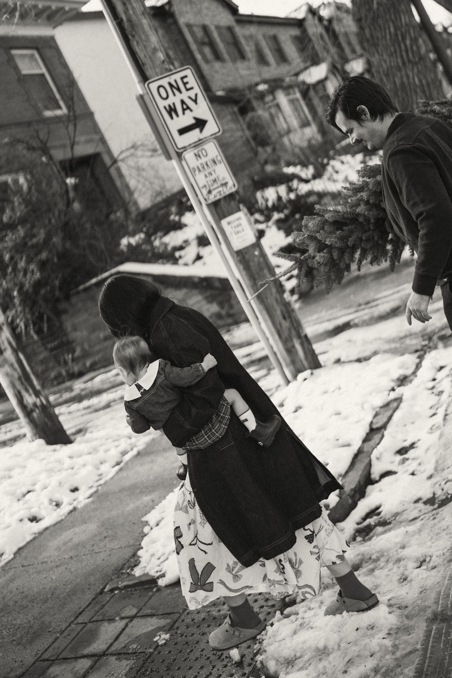 Black and white photos of people playing in snow on an urban street.