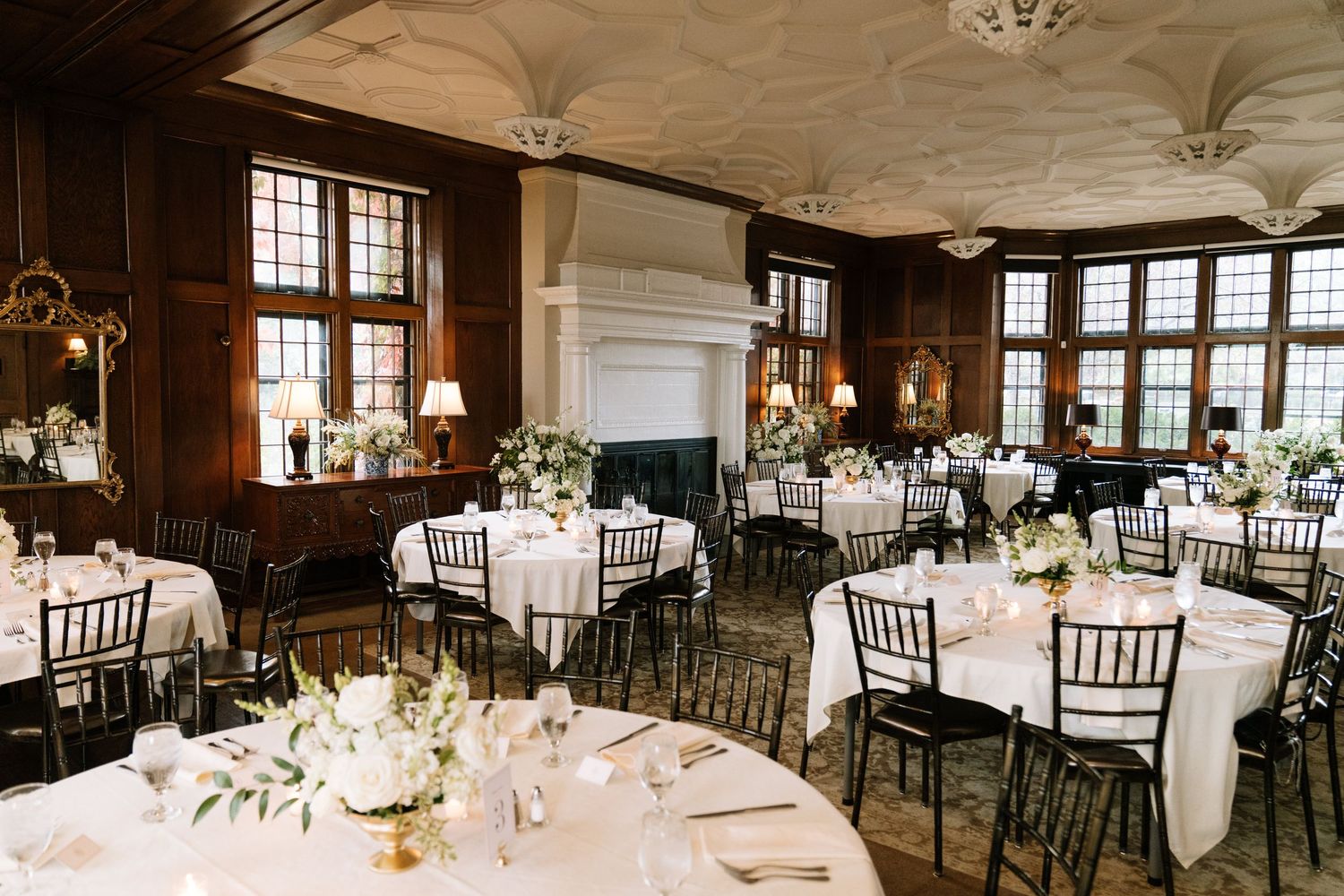 Elegant wedding reception hall with round tables and classic chiavari chairs set for dining.