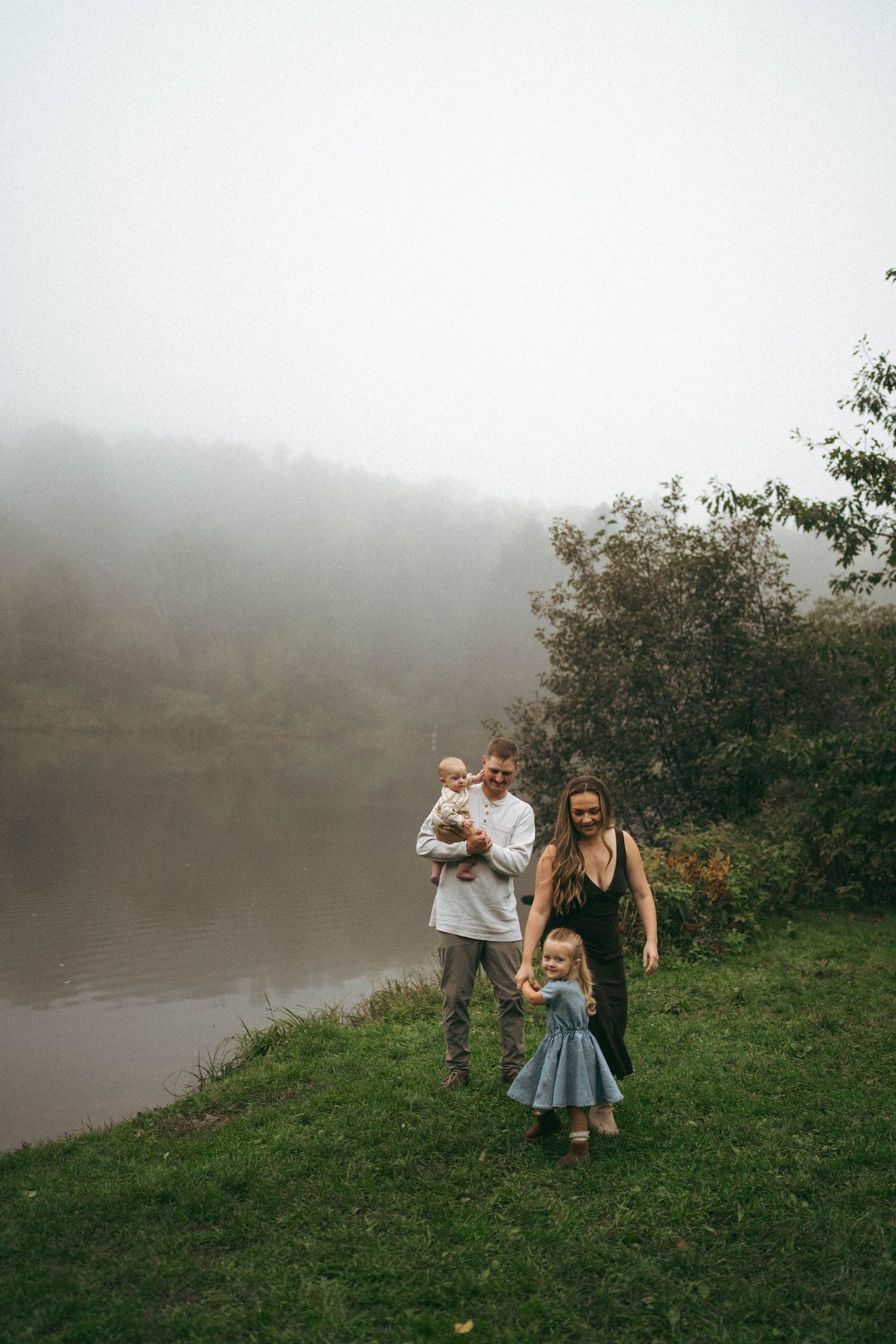 A group enjoying time together on a grassy hill overlooking a misty lake.