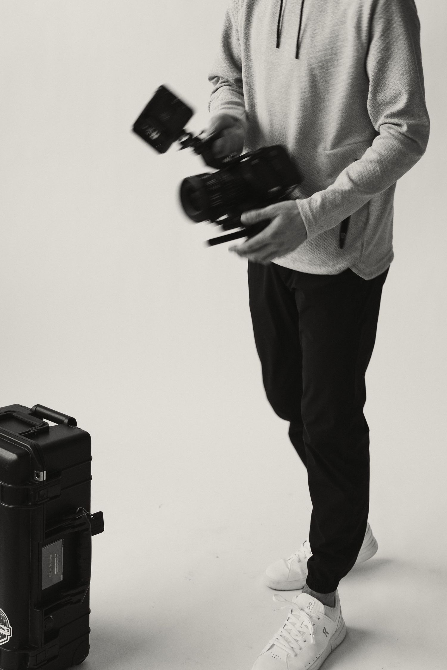 Photographer demonstrating camera equipment handling in casual studio setting.