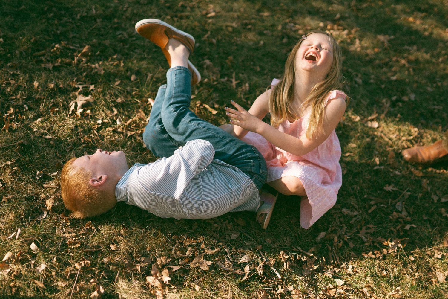 People enjoying a playful moment together on sunlit grass.