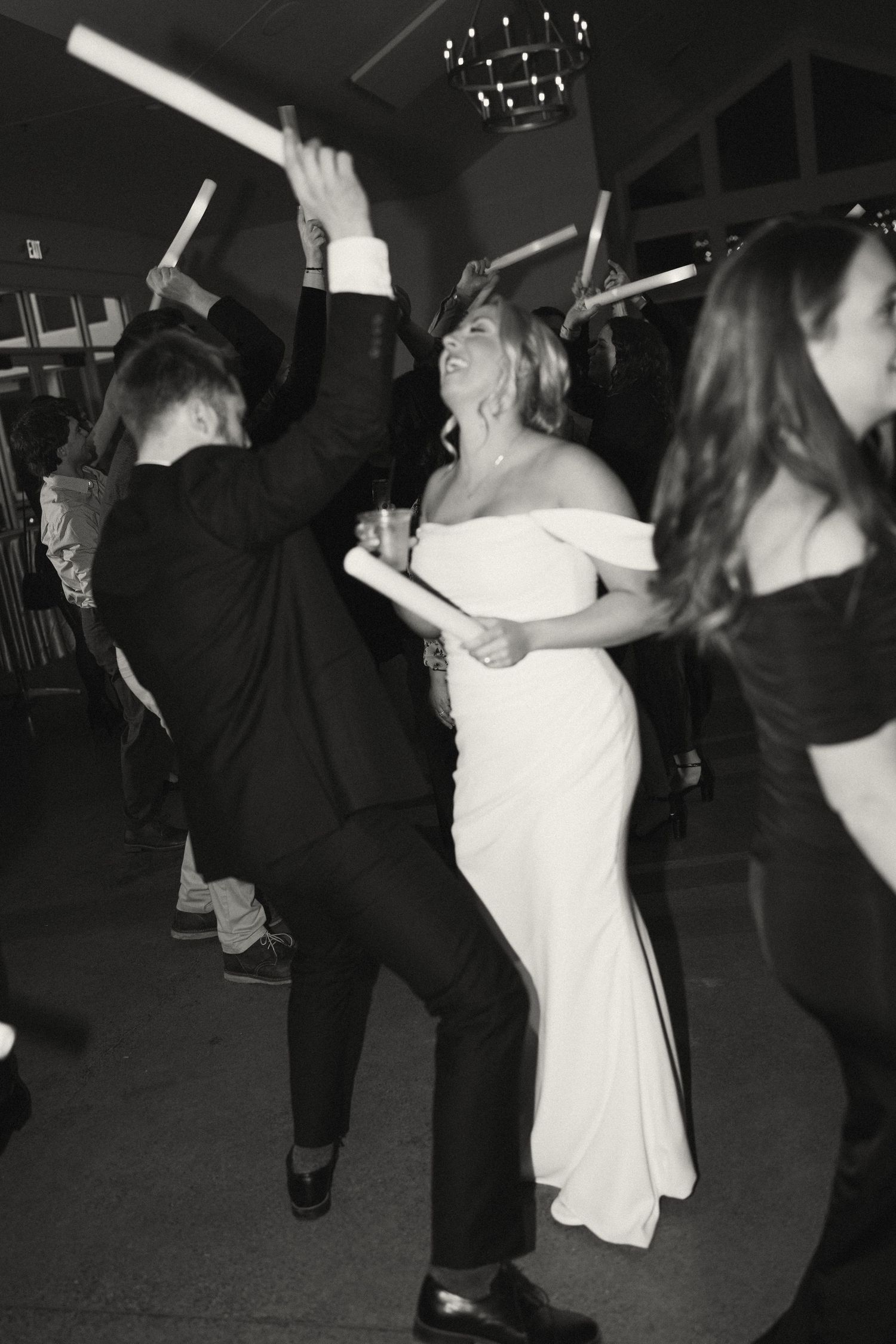 Wedding guests dancing with glow sticks on a dark dance floor.