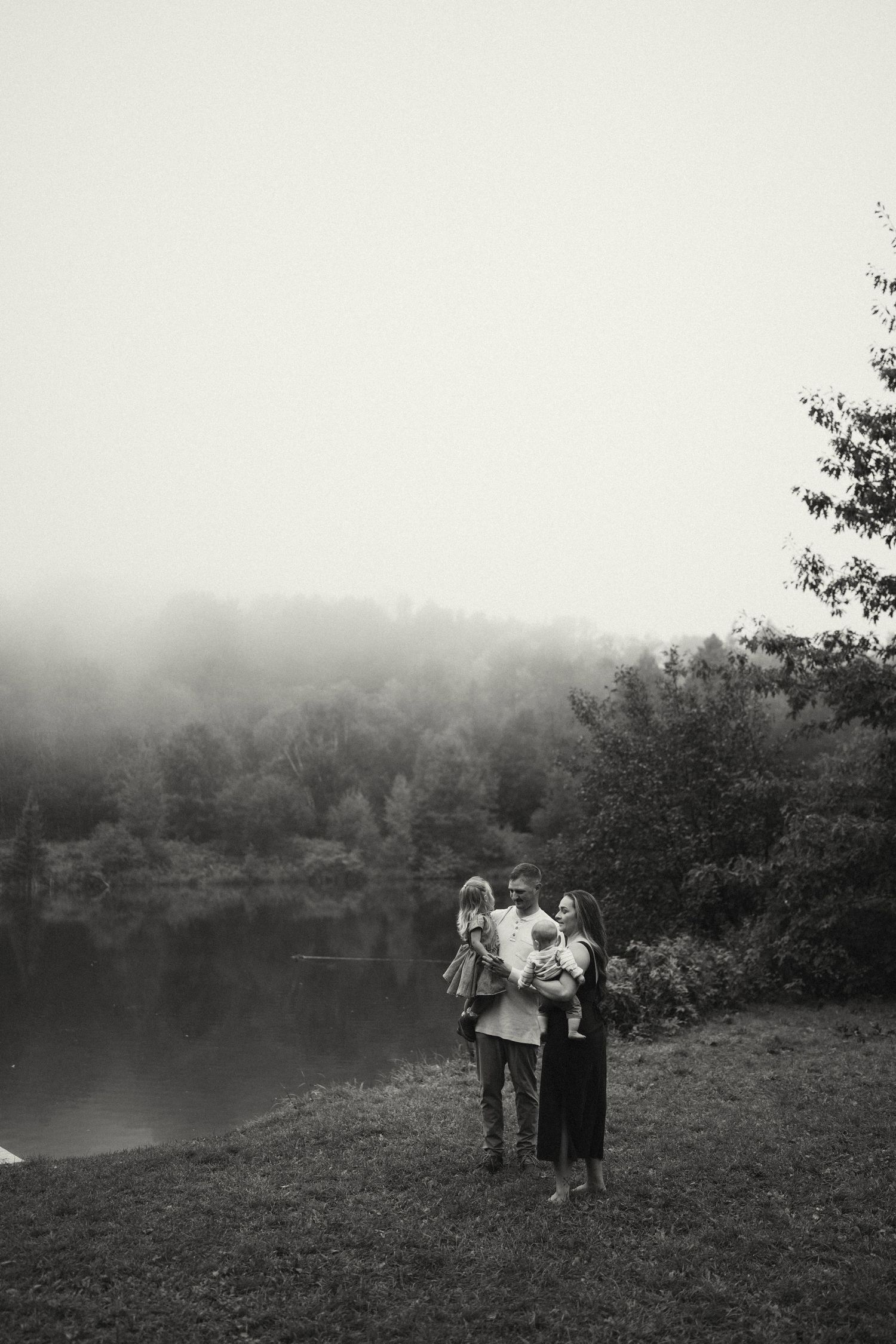 A group stands together on a grassy slope with fog rolling in behind them.