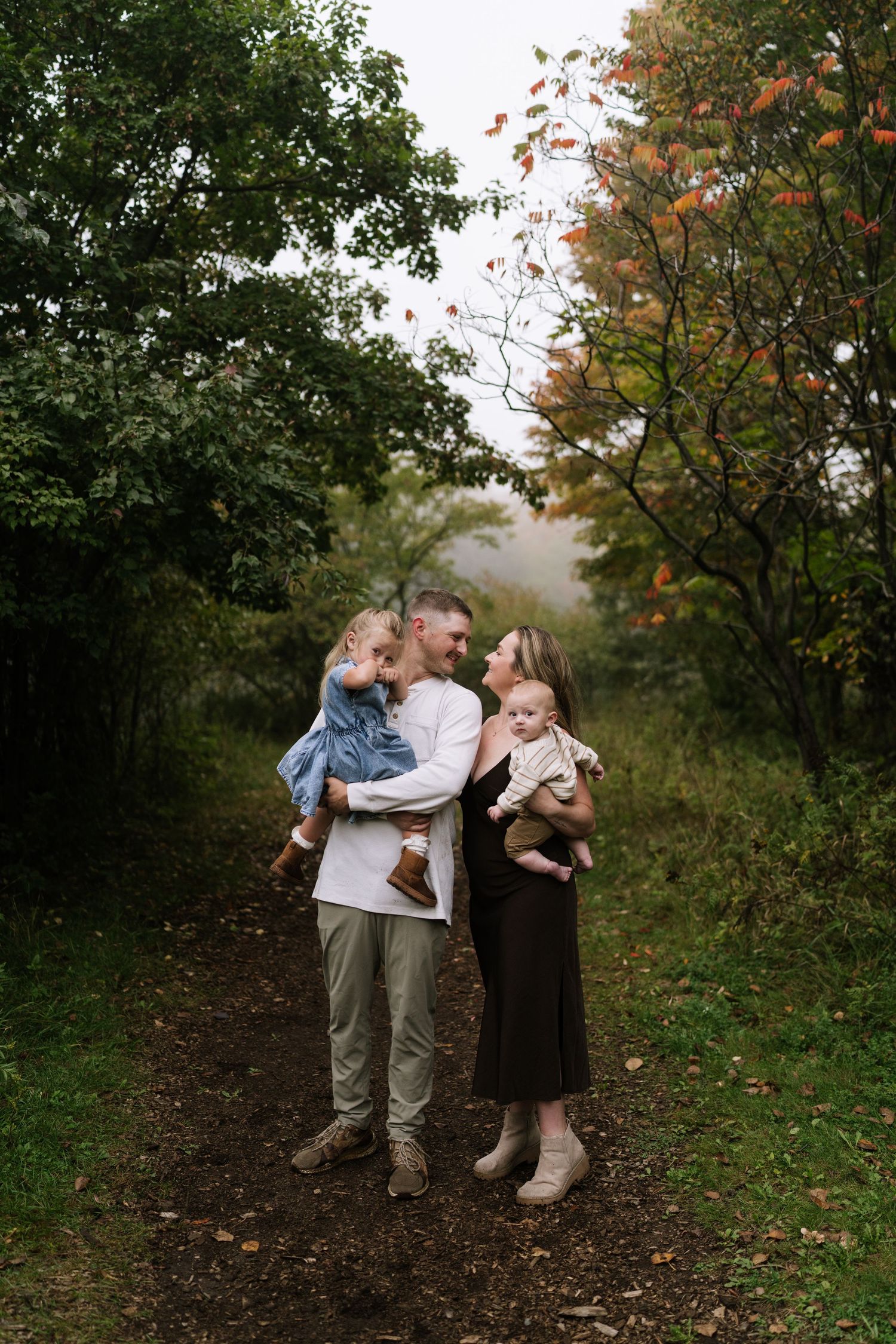 A sweet family moment captured on an autumn trail surrounded by fall foliage.