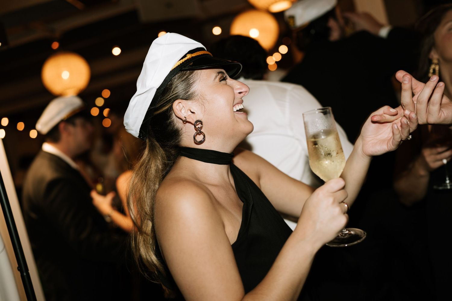 Party goers dance and celebrate with drinks in hand at a dimly lit nighttime celebration.