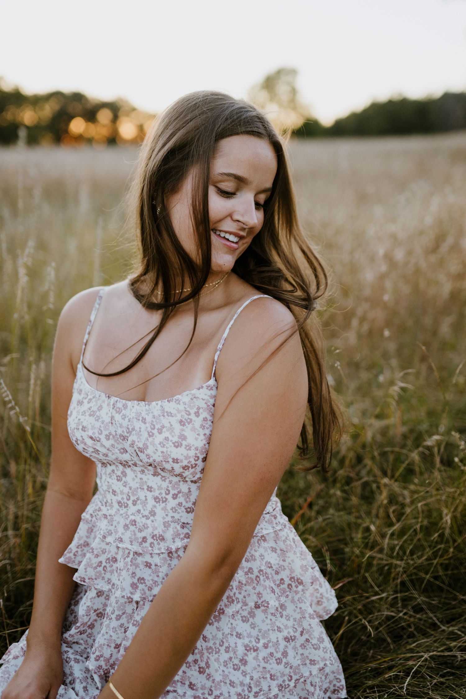 Summer portrait session featuring a delicate white floral dress in a rustic field setting.