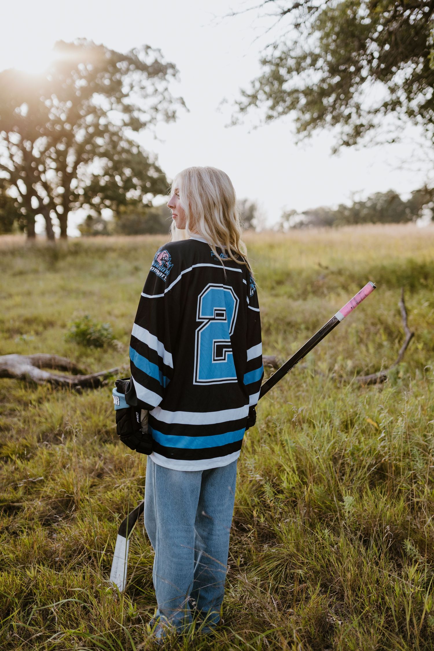 Person wearing hockey jersey number 2 standing in field holding hockey stick.