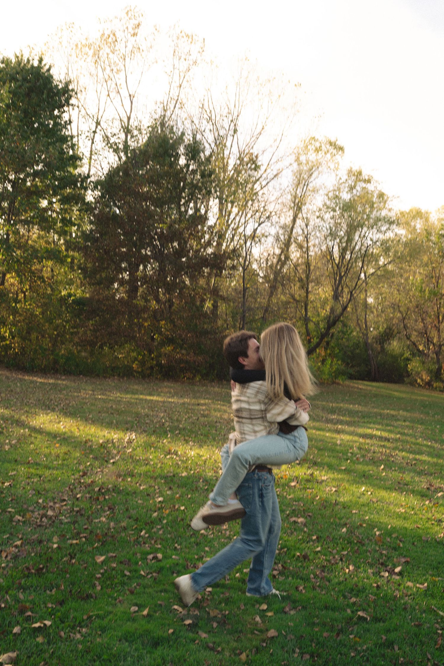 A playful sequence of photos showing a couple embracing and spinning in a grassy field at sunset.