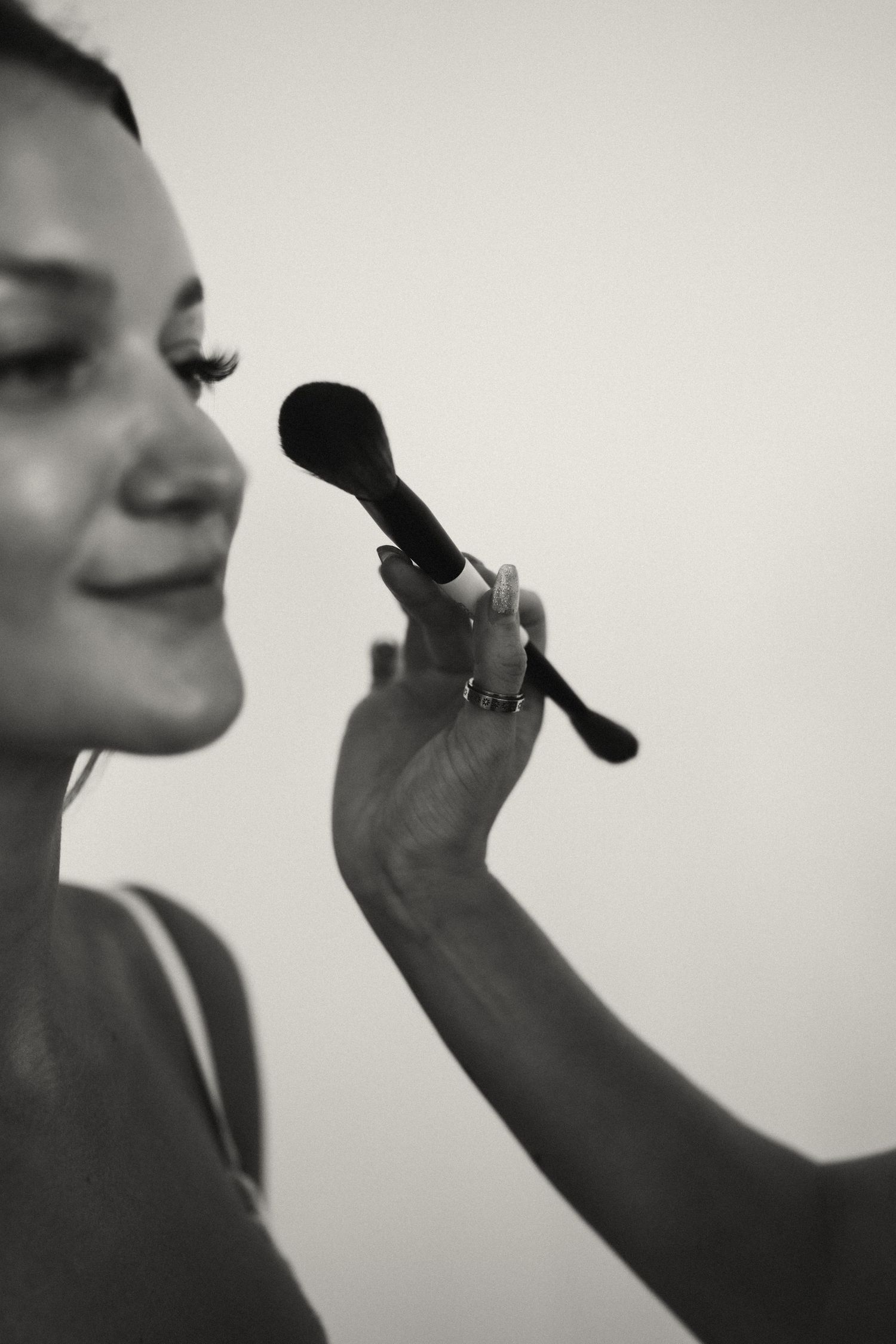 Black and white close-up of someone holding a makeup brush.