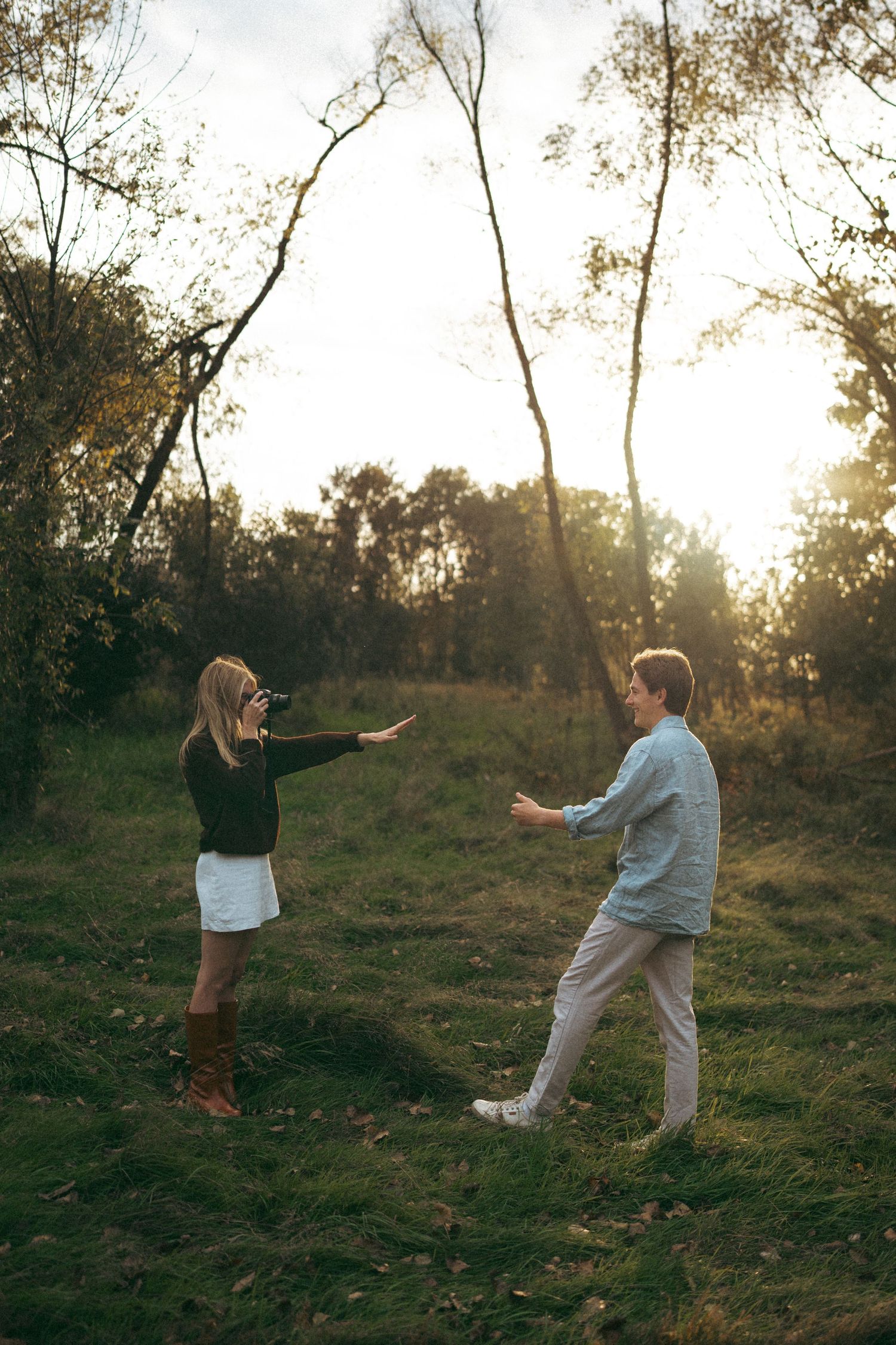 Playful interaction between two people on a grassy hillside at sunset.