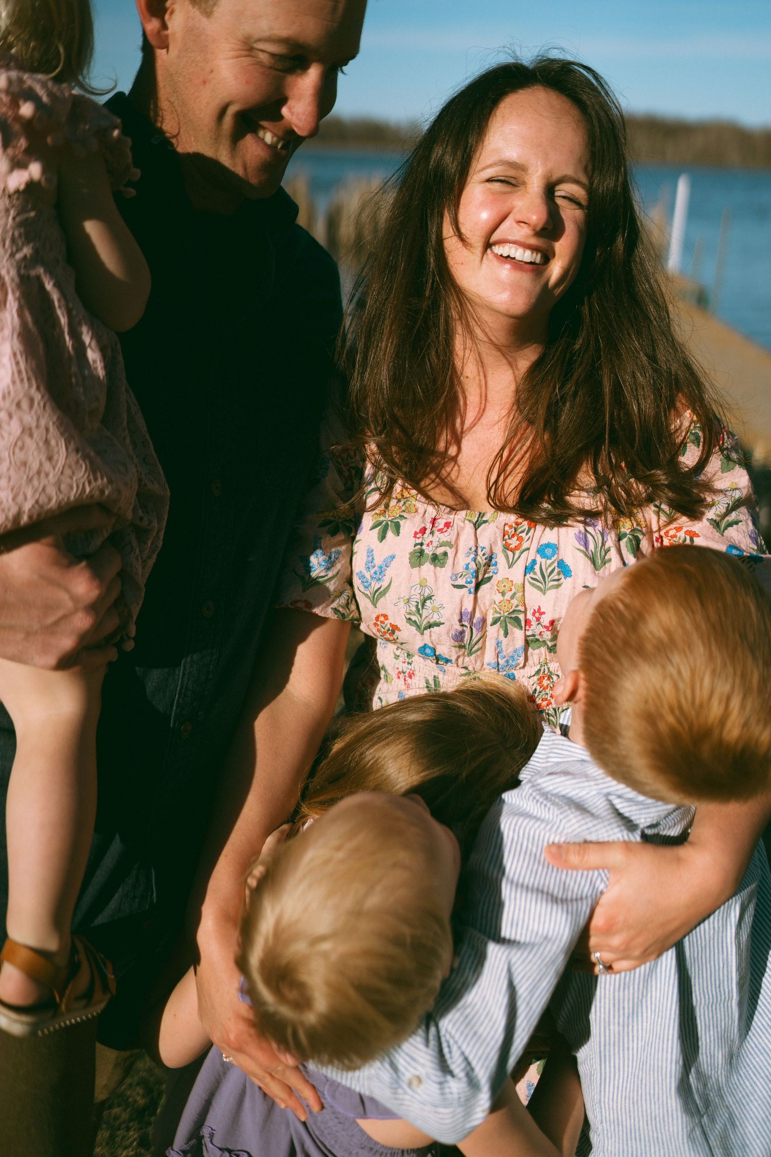 A joyful outdoor family portrait session by the water on a sunny day.