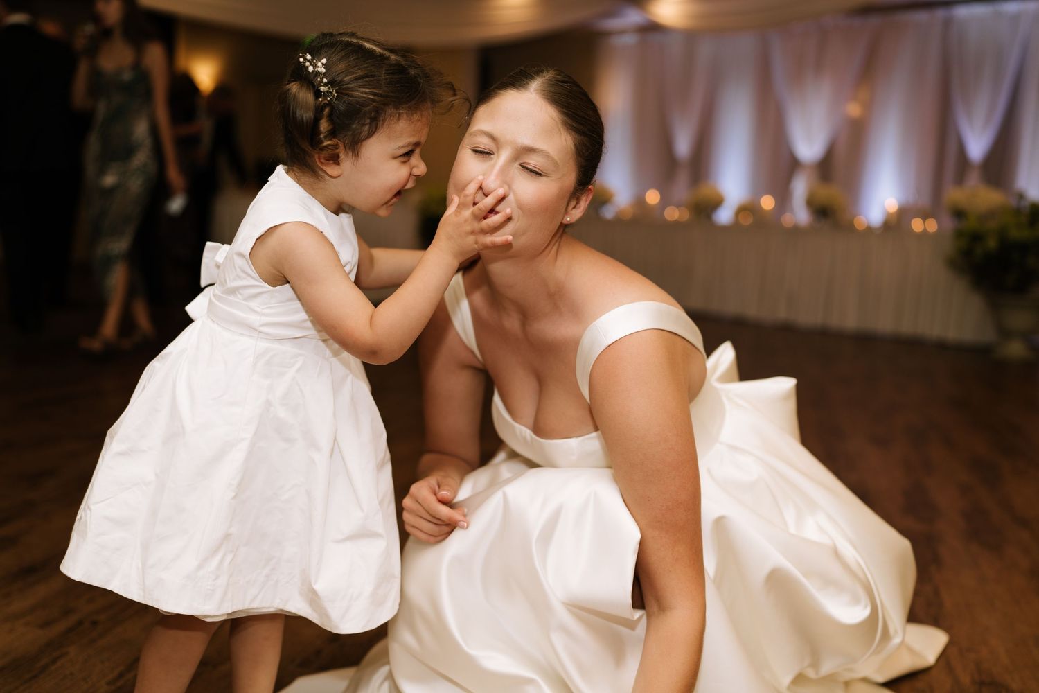 Sweet moment shared between bride and flower girl during wedding reception.