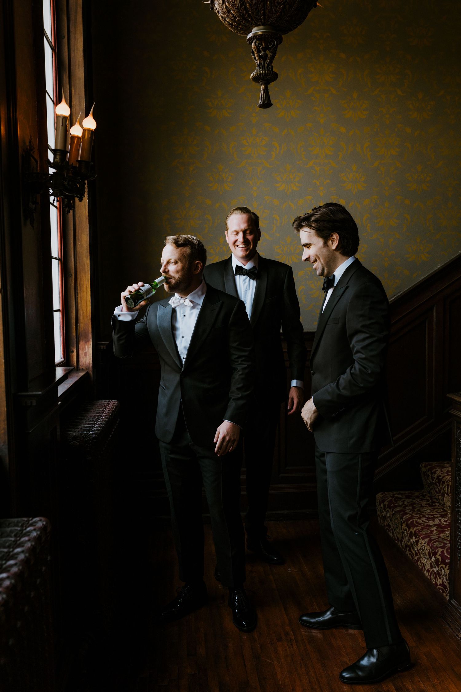 Group of men in formal attire sharing candid moments in a dark, moody setting.