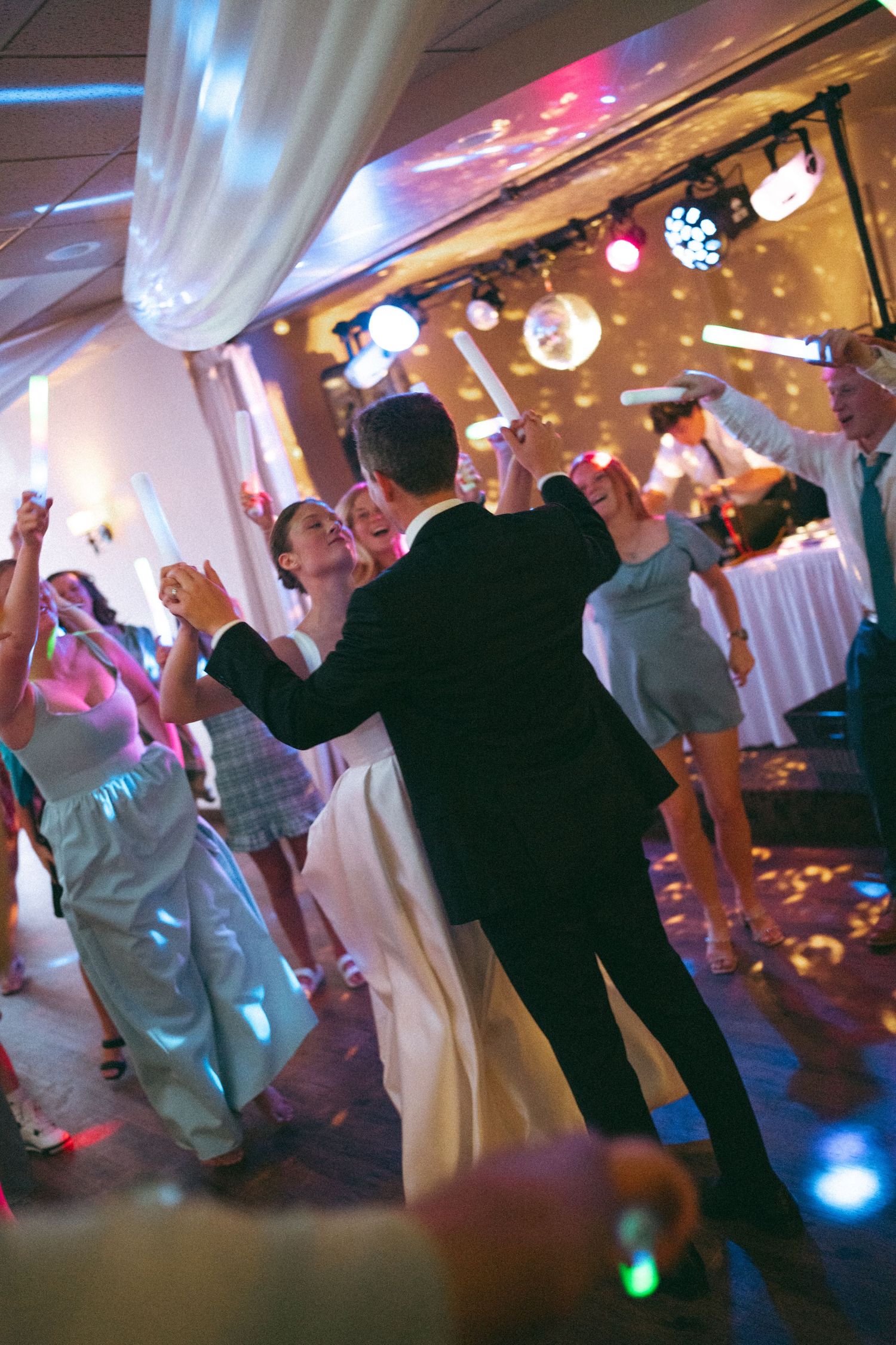 Wedding reception dance floor with colorful lights and dancing guests.