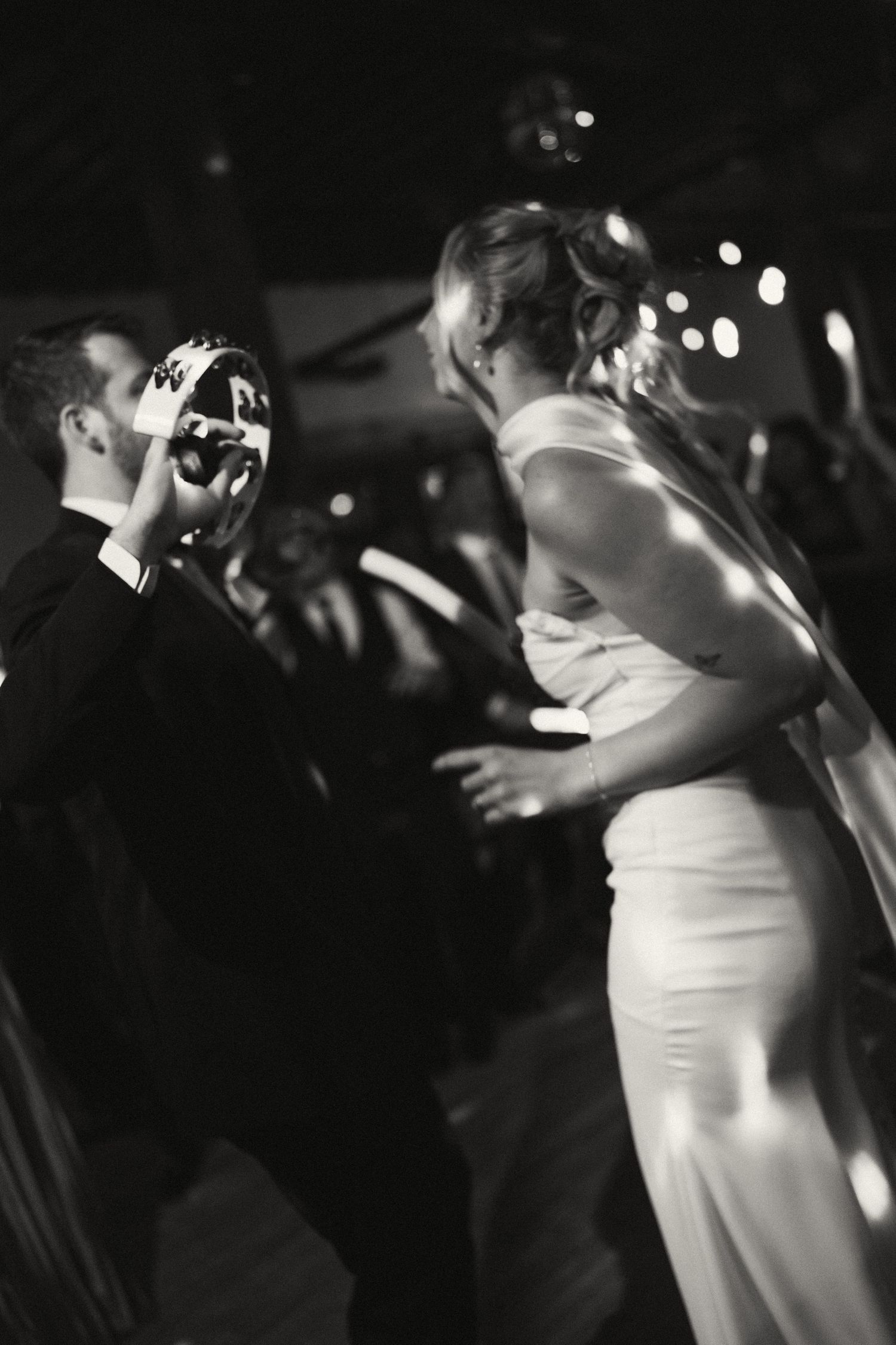 Black and white photo of couples dancing closely on a dimly lit dance floor.