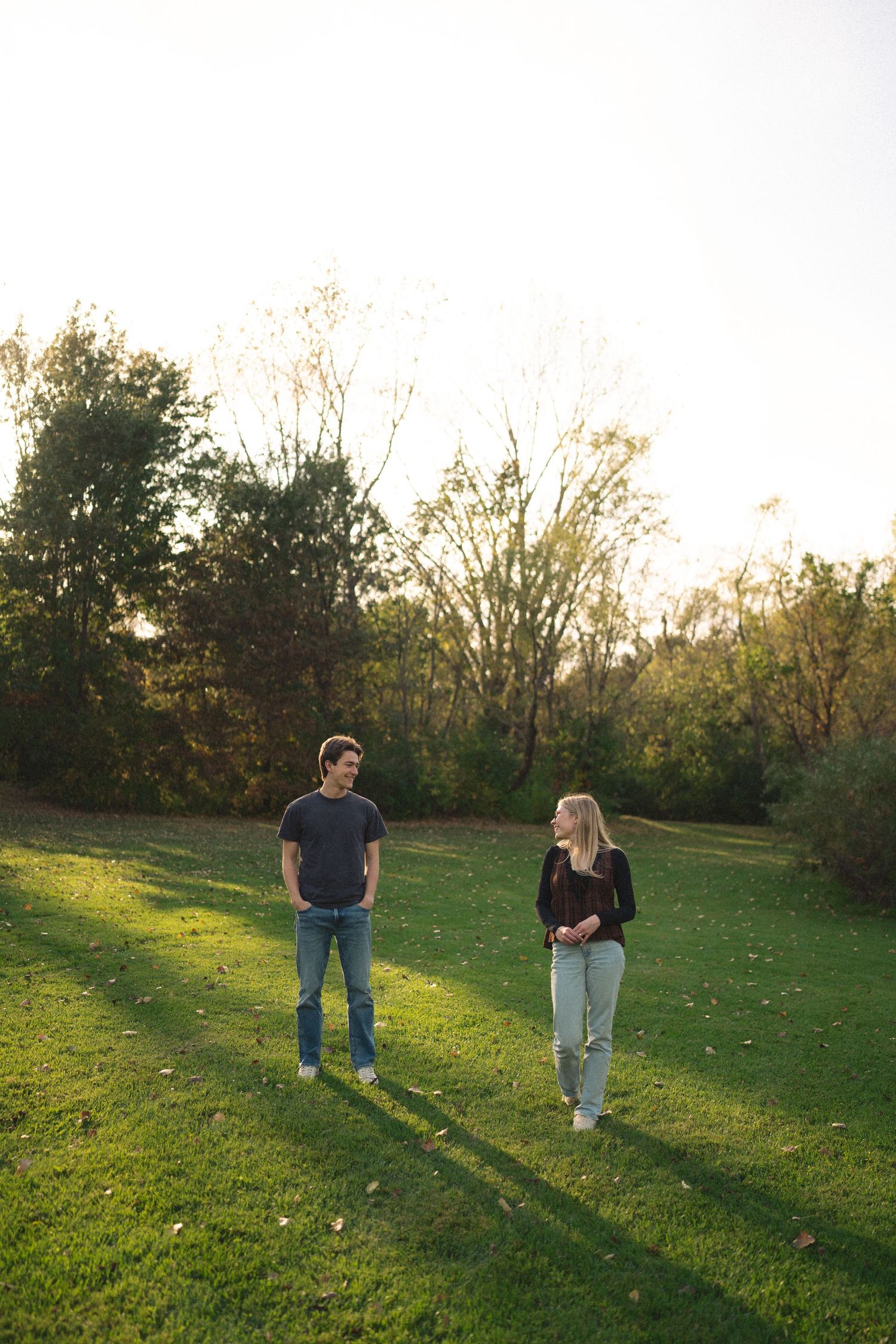 Two people standing in a sunlit meadow during golden hour.