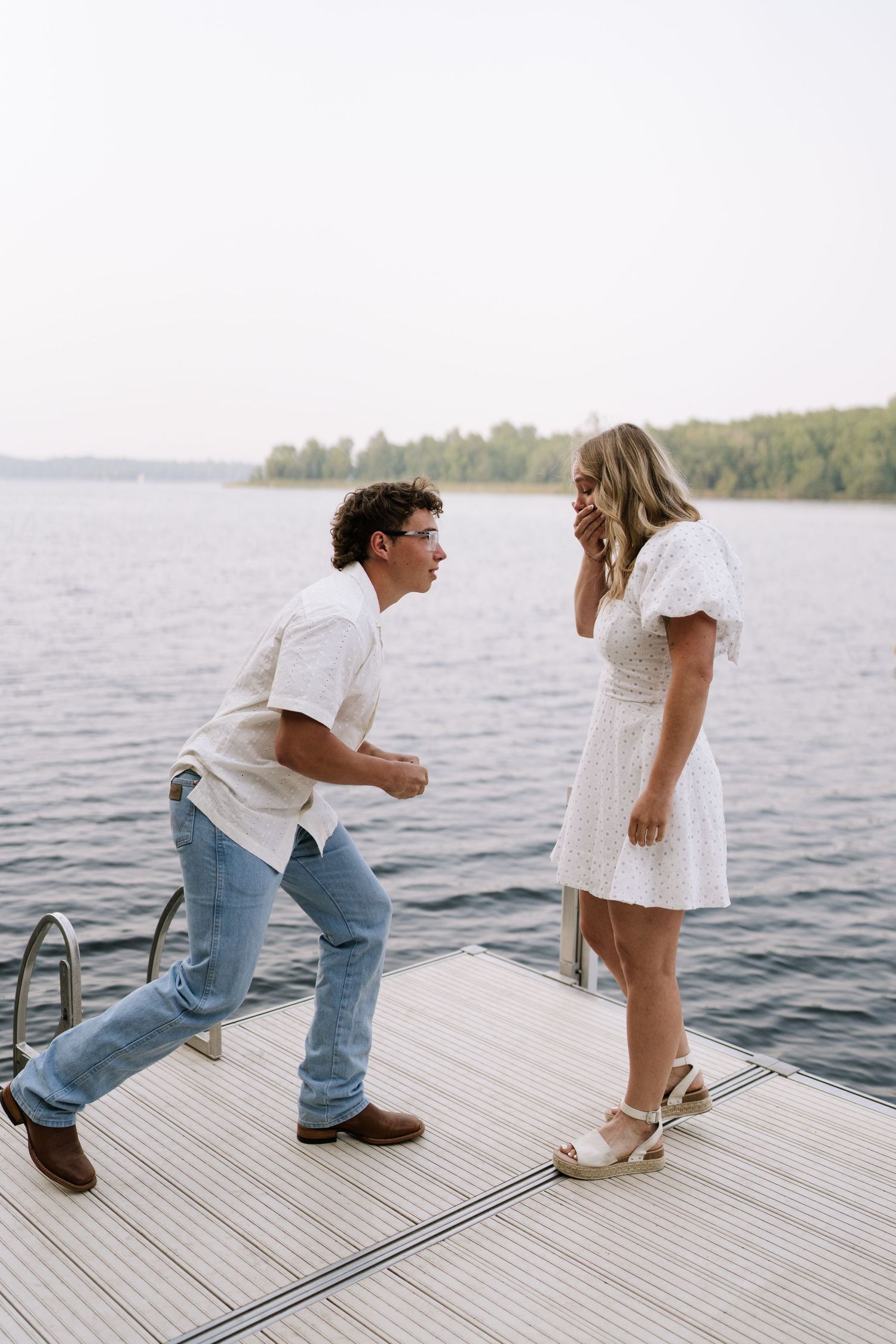 A proposal moment captured on a lakeside dock during summer.