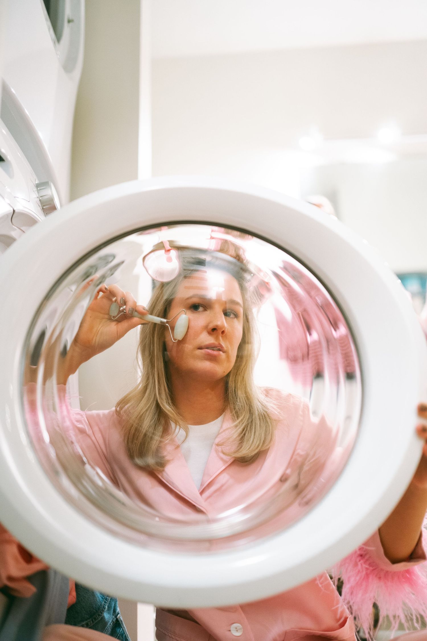 Looking through a washing machine door with reflections in pink tones.