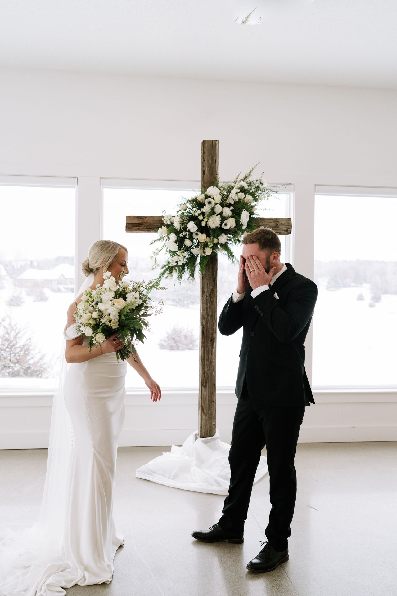 First look wedding photos in a bright modern white room with floral arrangements.