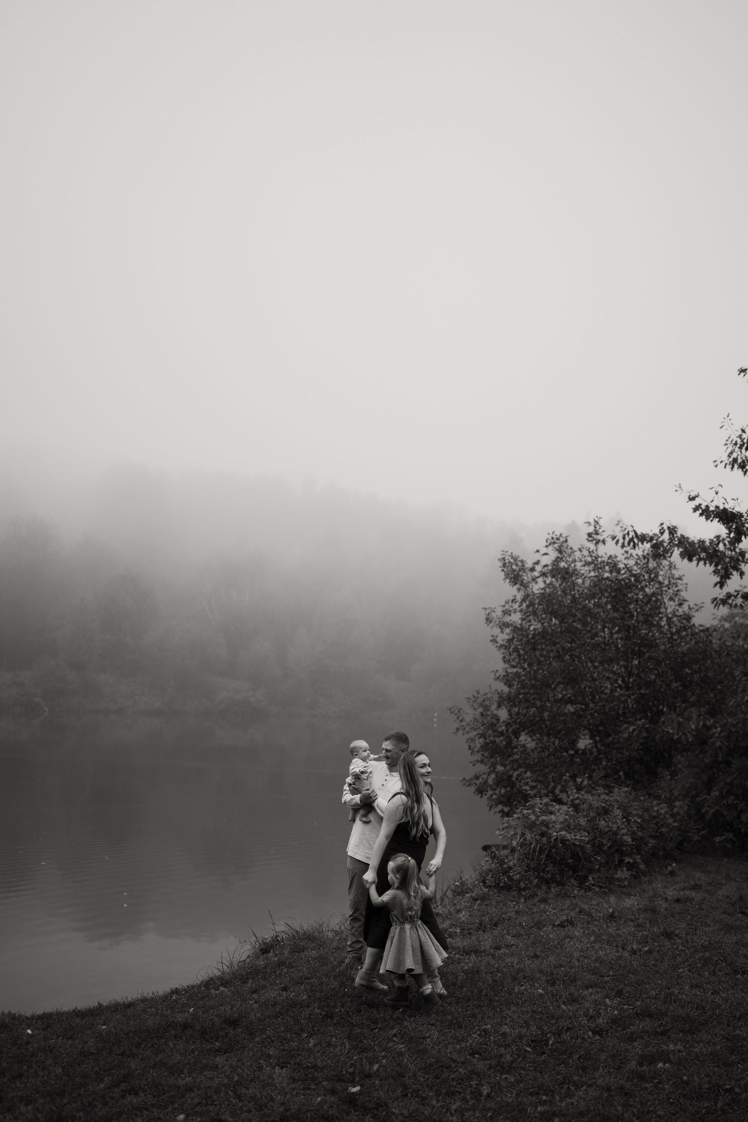 Misty black and white photo of a couple embracing by a lake.