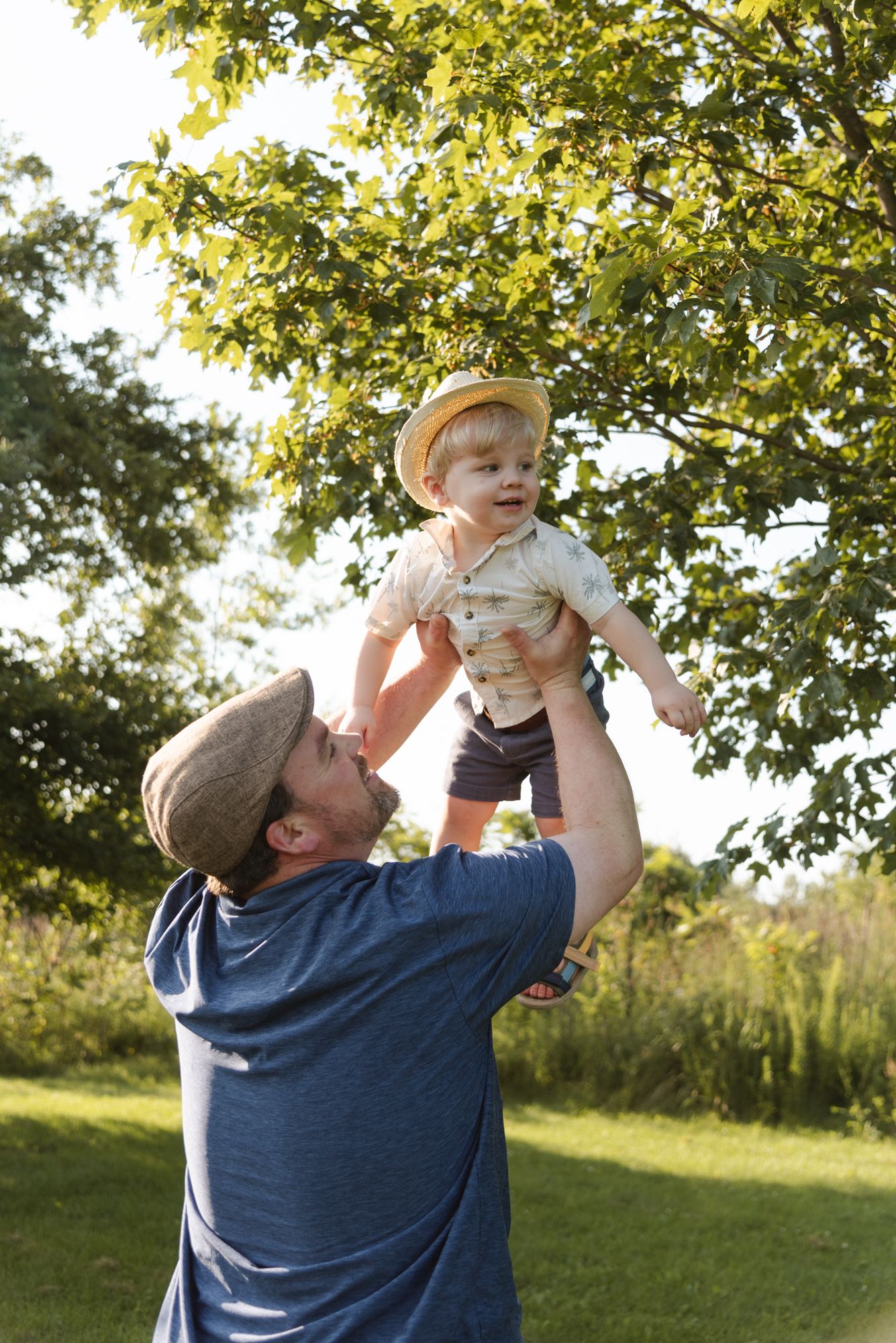 Father lifting his smiling son into the air during family photos at Centennial Lilac Garden in Niagara Falls