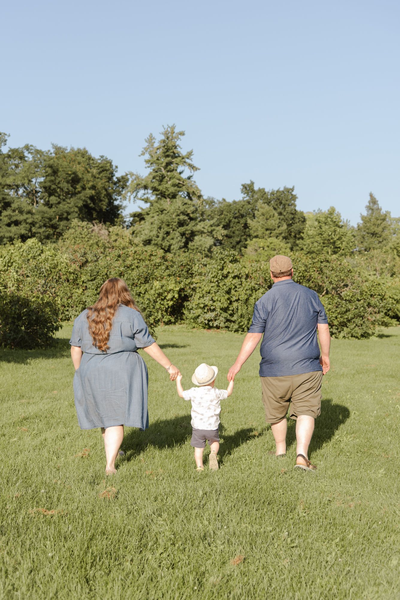Parents walking through the grass with their son during relaxed family photos in Niagara Falls, Ontario
