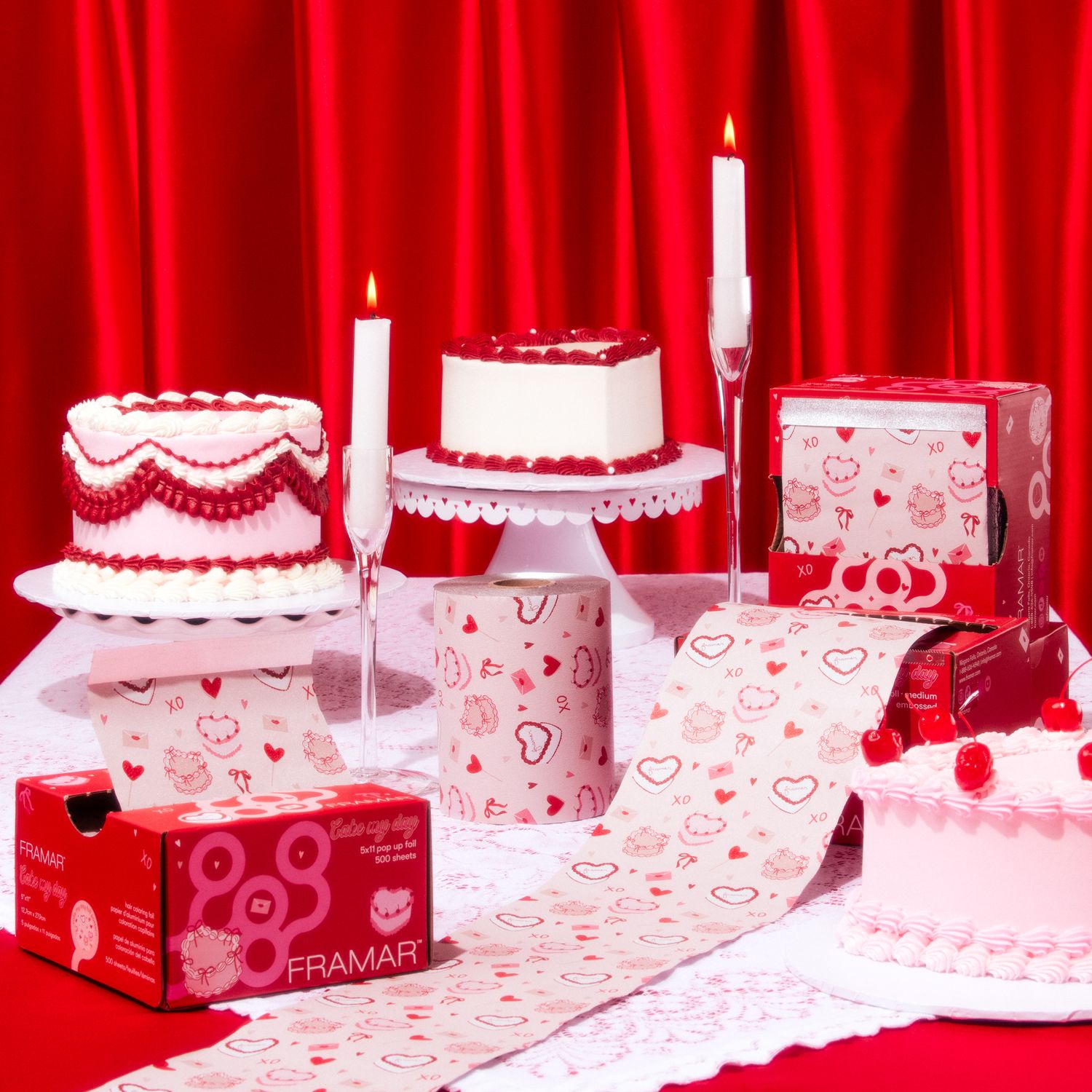Studio product photography of hair foil packaging styled with pink and red cakes, candles, and Valentine-themed decor on a red backdrop