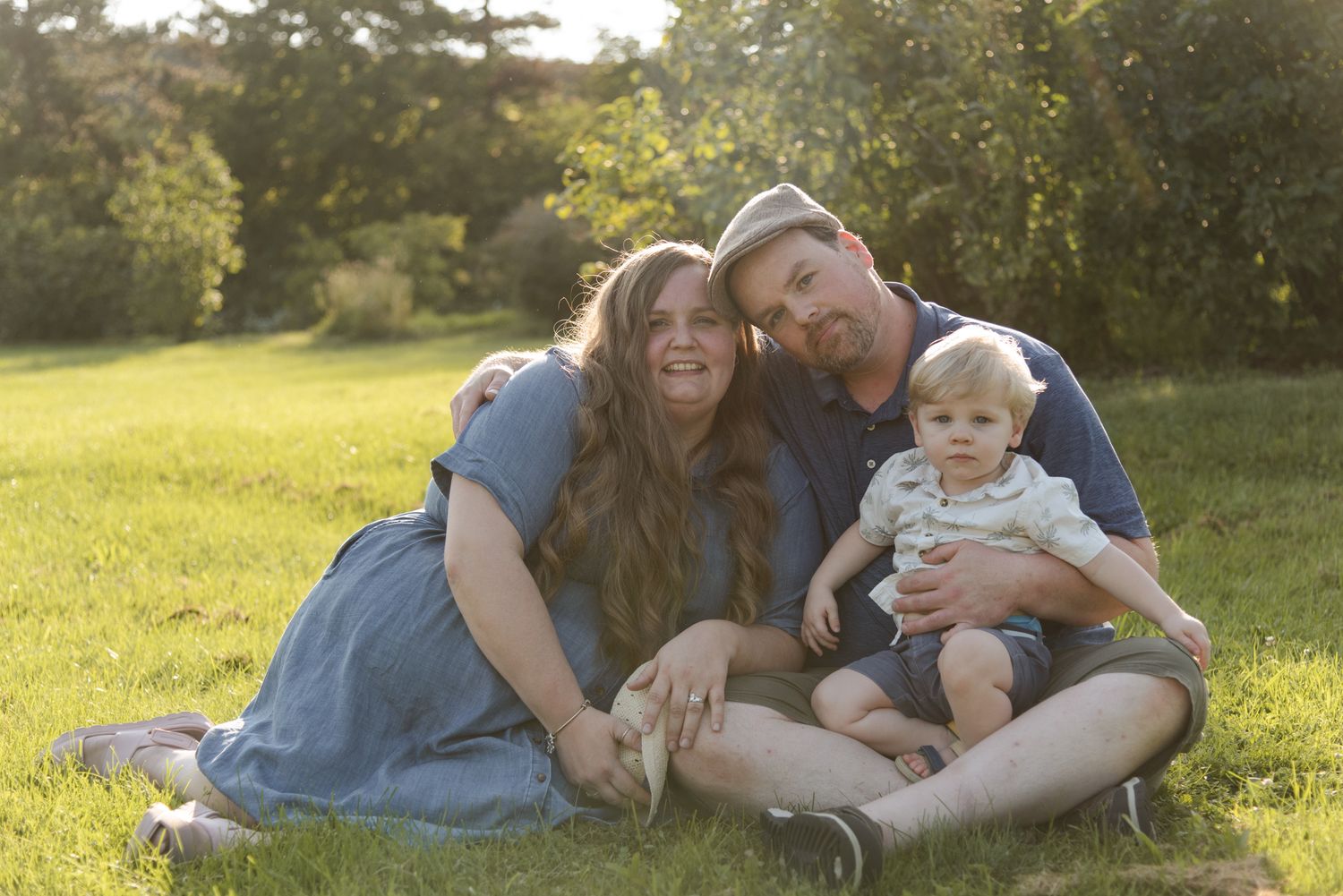 Family sitting together in the grass for a relaxed portrait at Centennial Lilac Garden in Niagara Falls