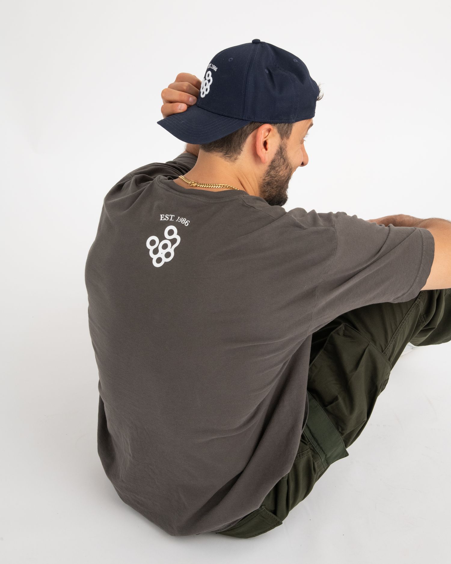 Studio lifestyle photo showcasing Framar branded merch, featuring a model wearing a logo t-shirt and hat against a clean white background.