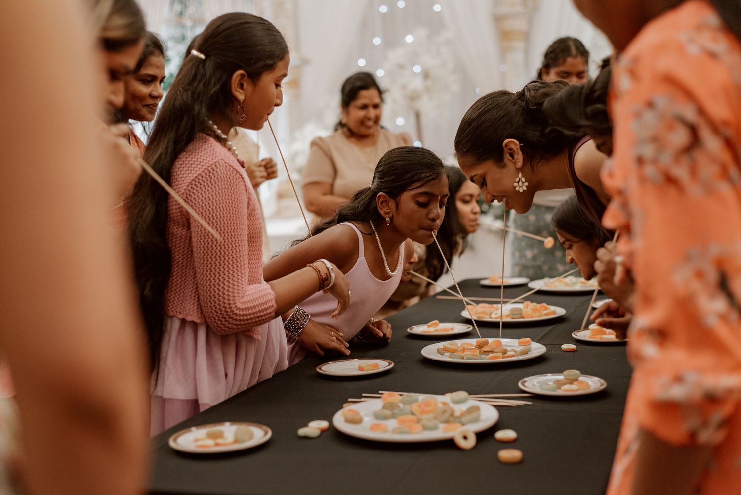 Candid bridal shower moment of guests playing a game around a table, laughing and interacting during a joyful wedding celebration.