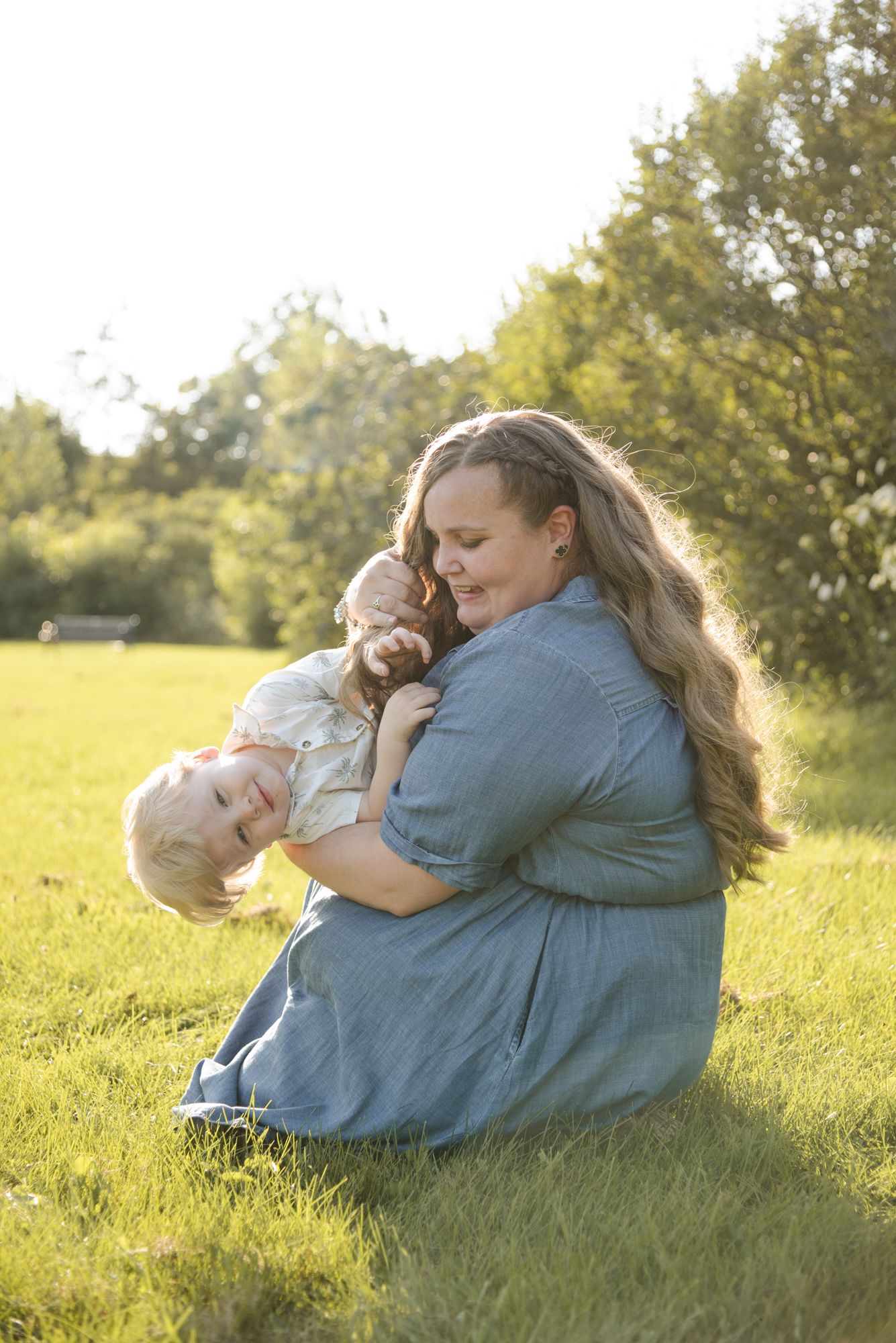 Mother cuddling her young son in the grass during family photos at Centennial Lilac Garden in Niagara Falls