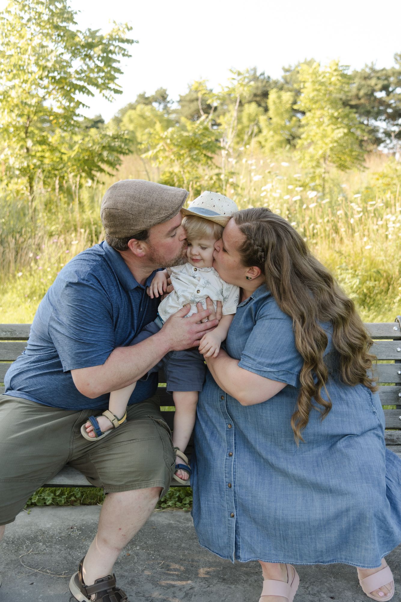 Parents kissing their young son during a candid family photo session at Centennial Lilac Garden