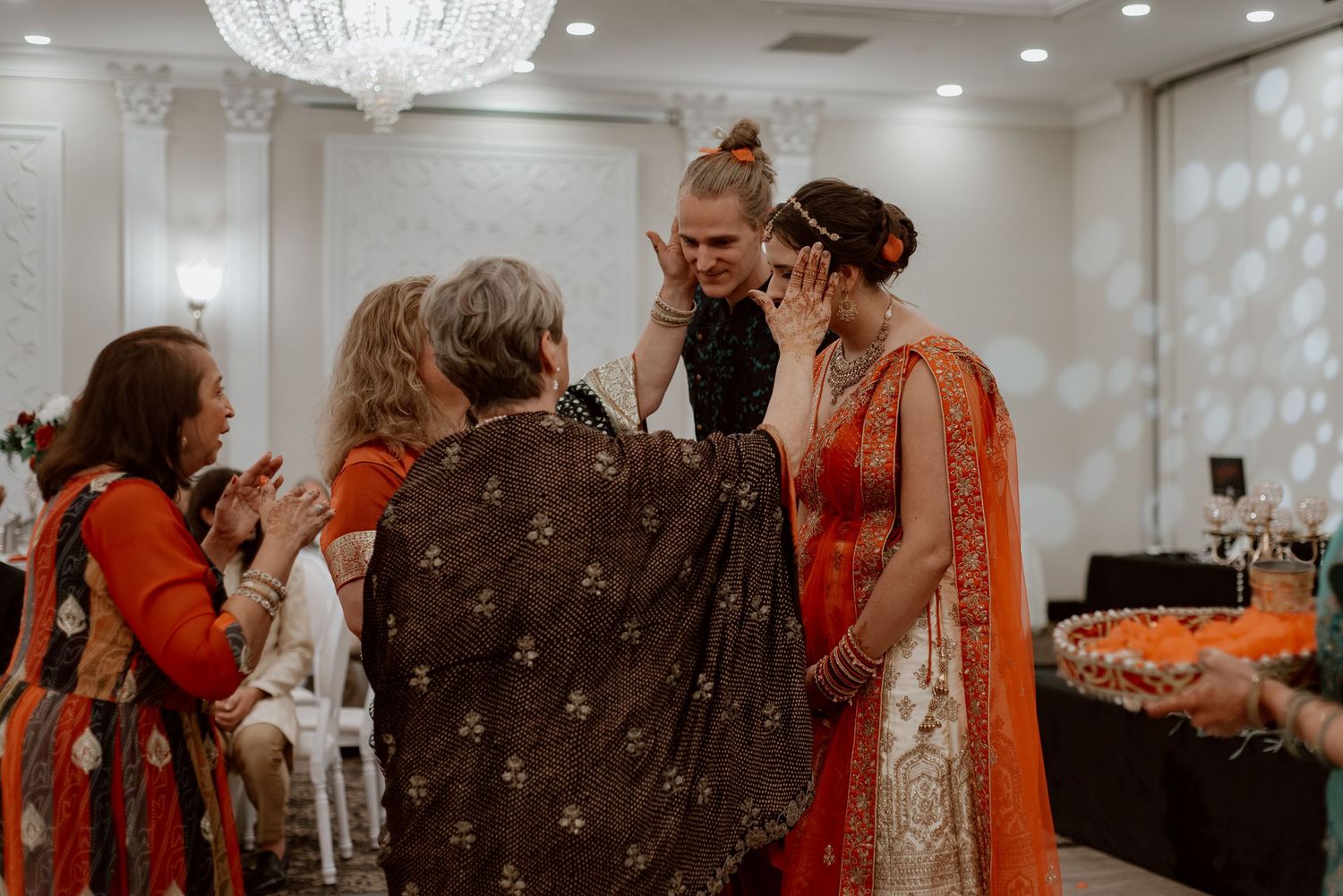 Candid Mandvo ceremony moment with family members blessing the couple, sharing an intimate cultural tradition during a wedding celebration.