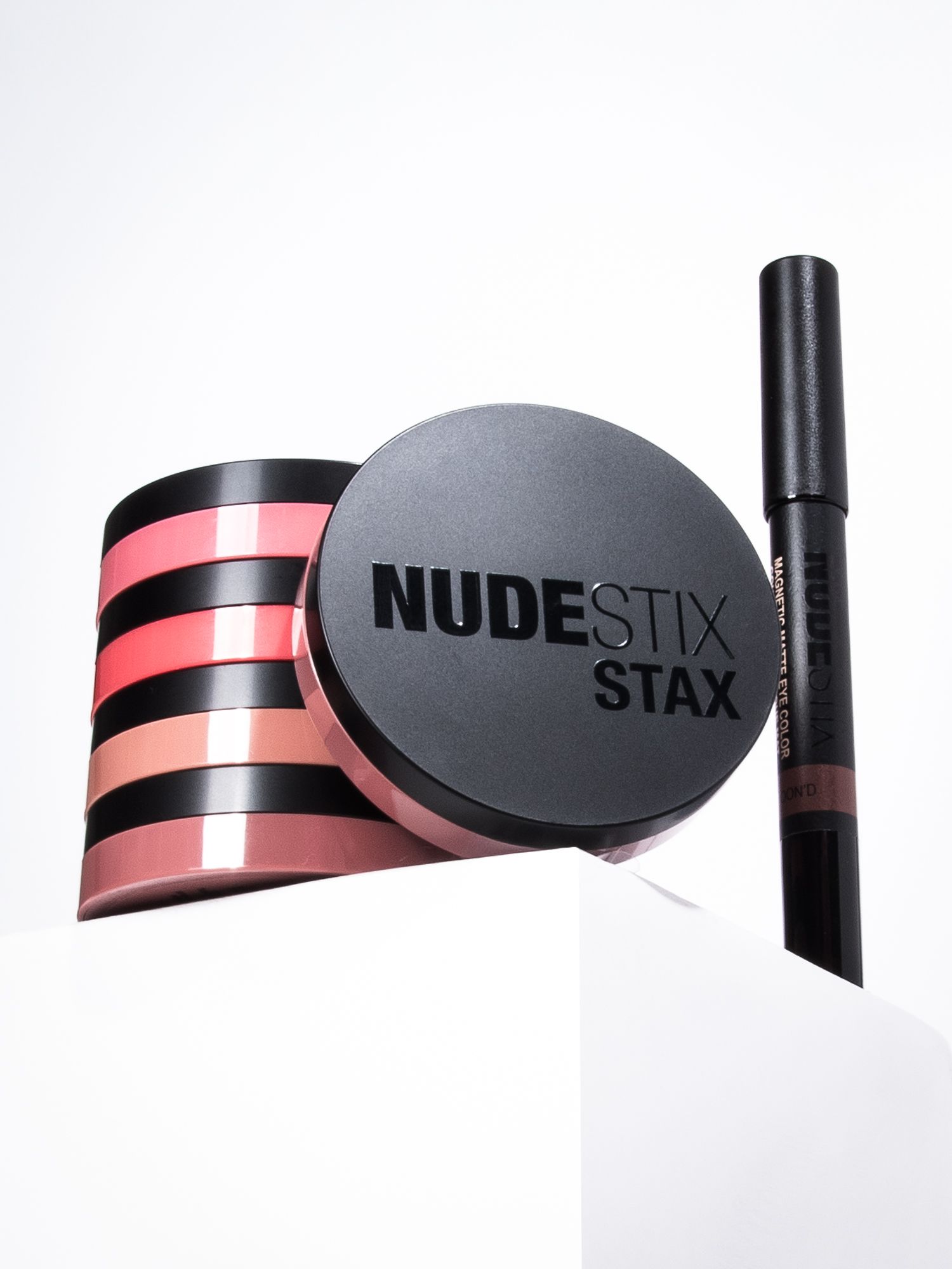 Commercial beauty product photography featuring Nudestix Stax blush palette and eye color on a white pedestal.