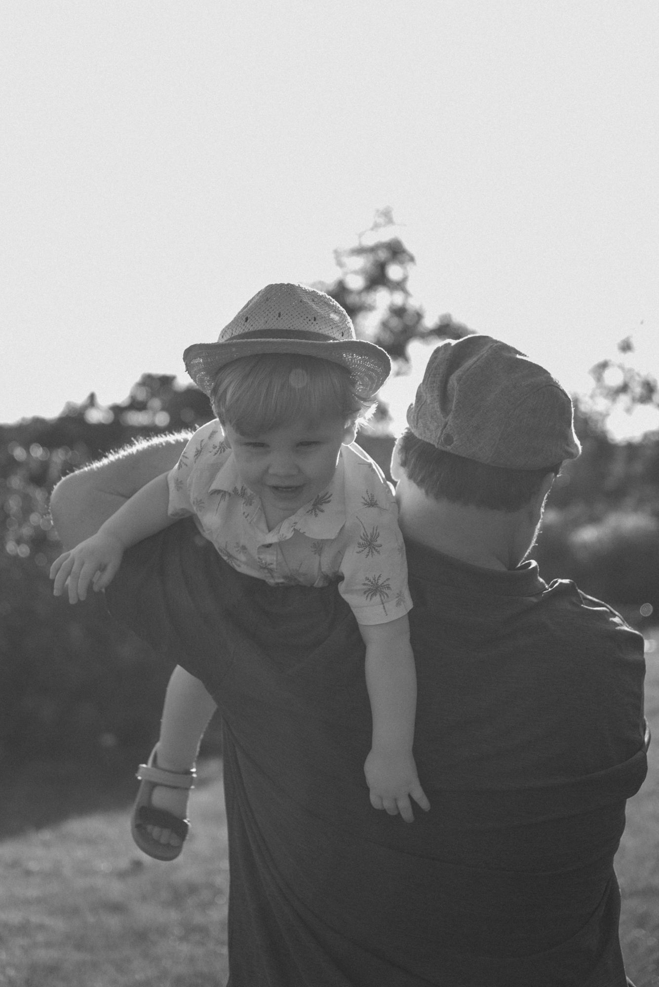 Black and white candid photo of a father carrying his young son during a Niagara Falls family photography session