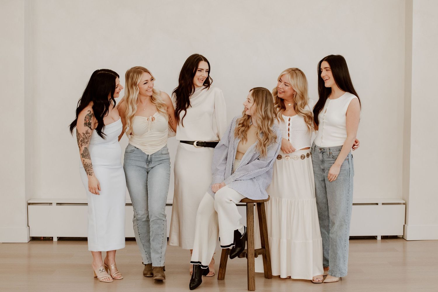 Studio branding portrait of a group of hairstylists standing together, smiling and interacting during a professional team photoshoot.