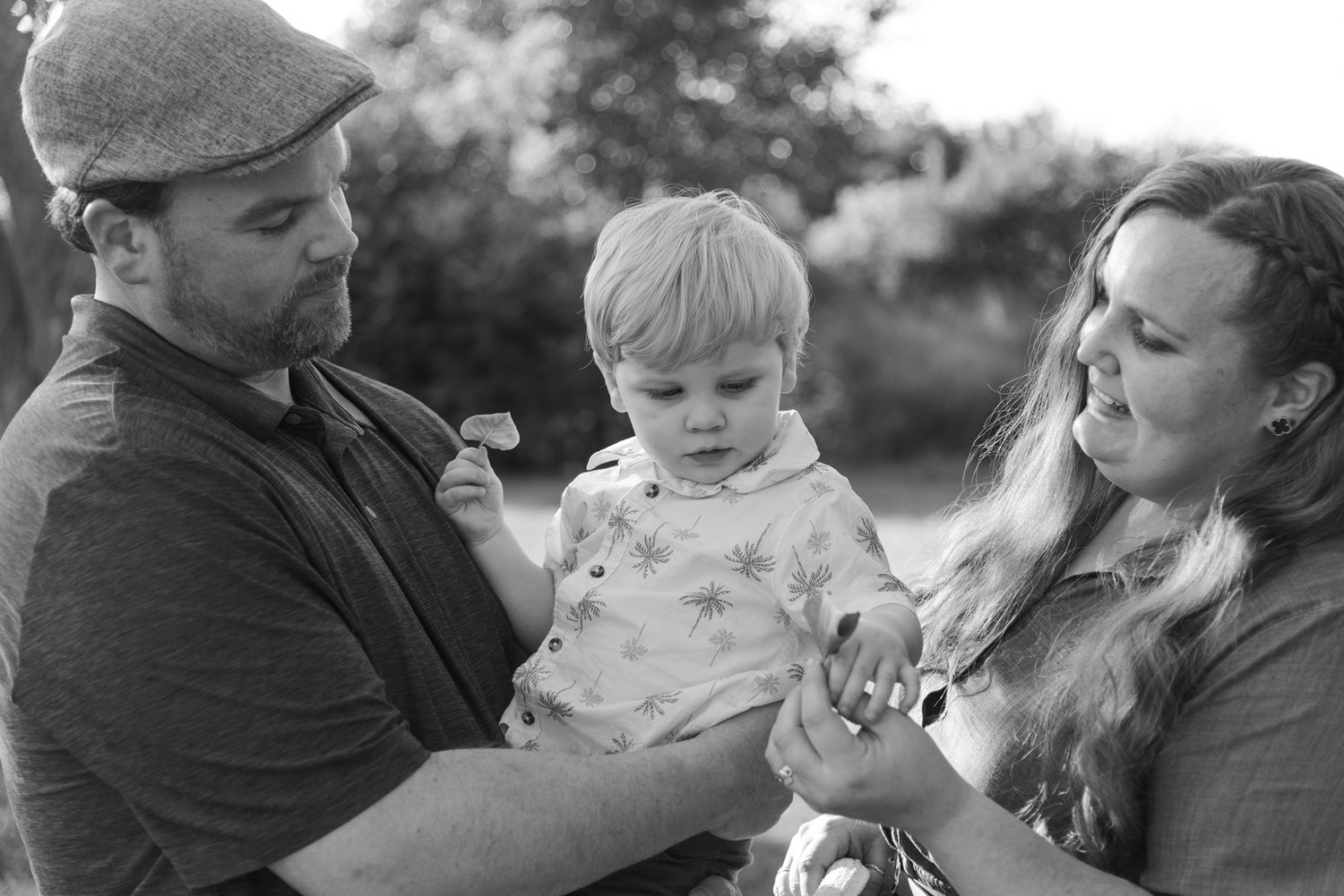 Black and white candid photo of parents playing with their young son during a Niagara Falls family photography session