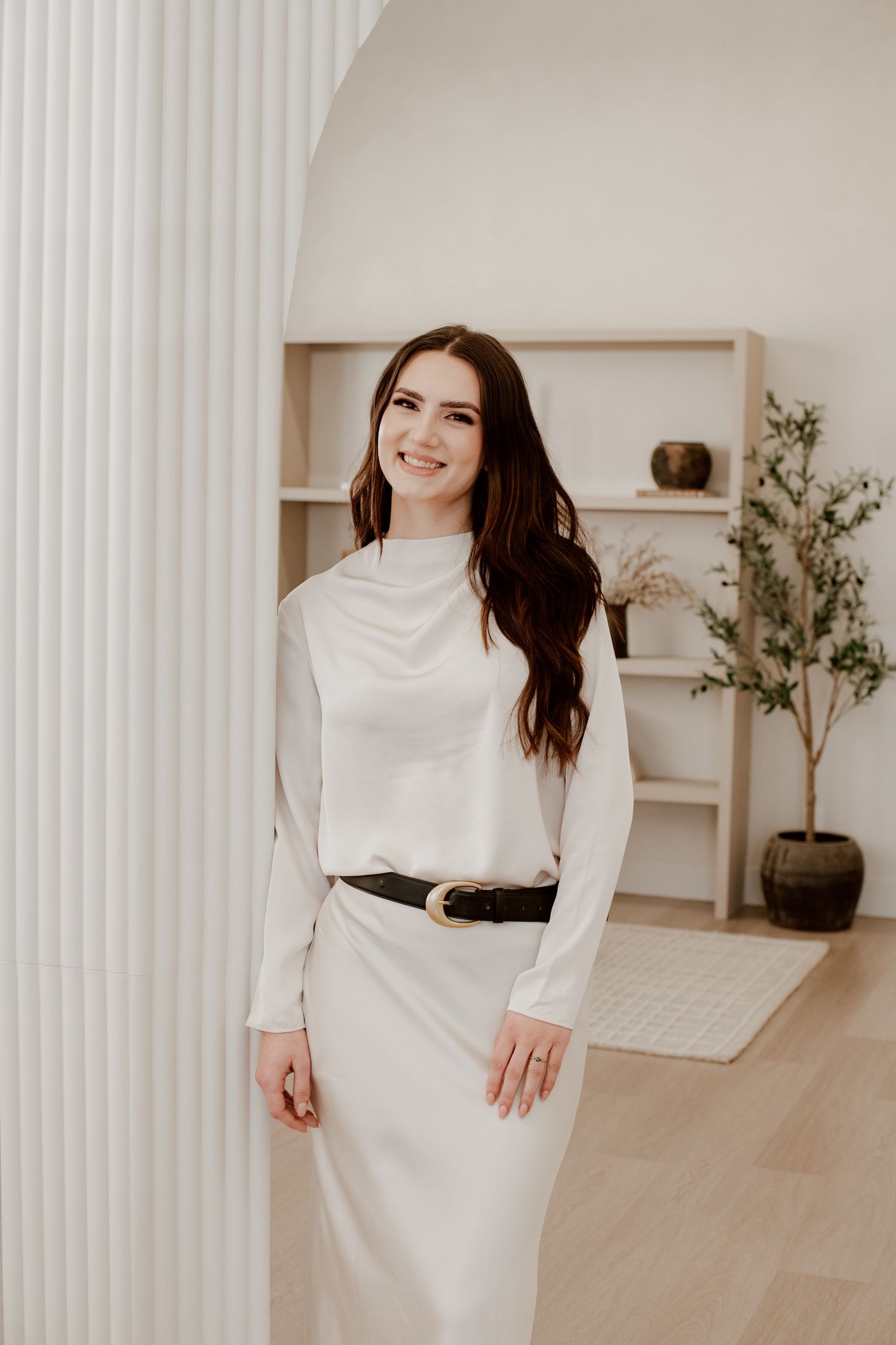 Branding portrait of a woman smiling indoors, styled in neutral tones and natural light for a modern personal brand photoshoot.