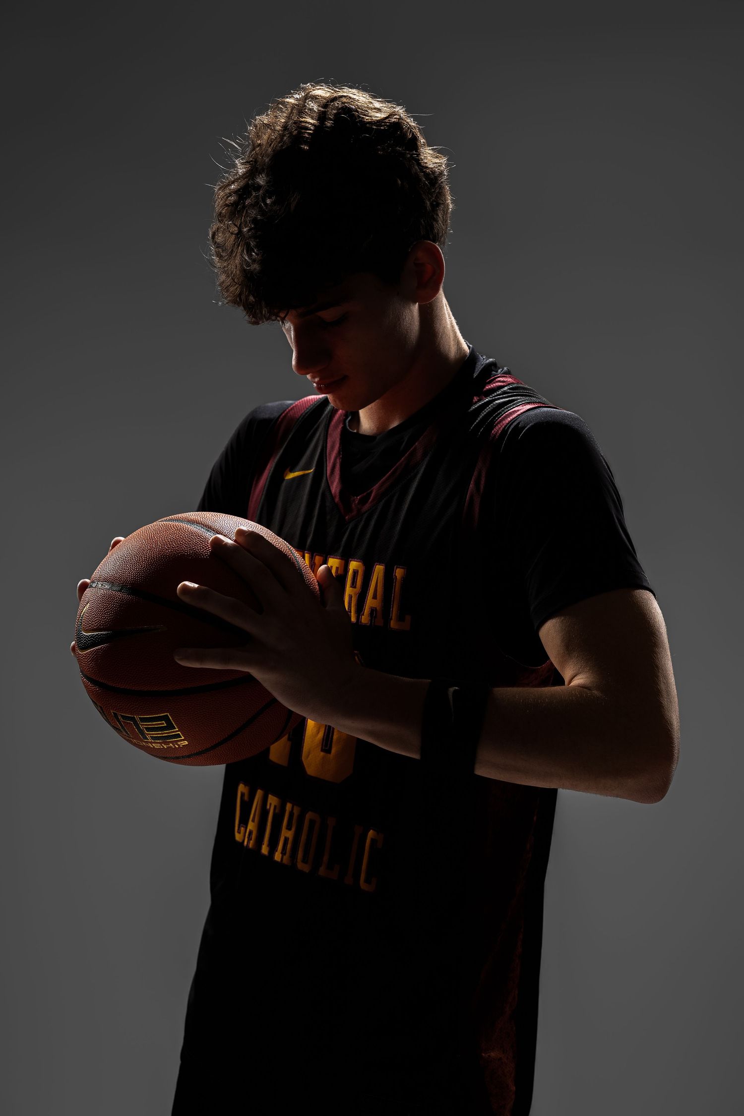 Dramatic silhouetted portraits of basketball player holding ball in dark lighting.