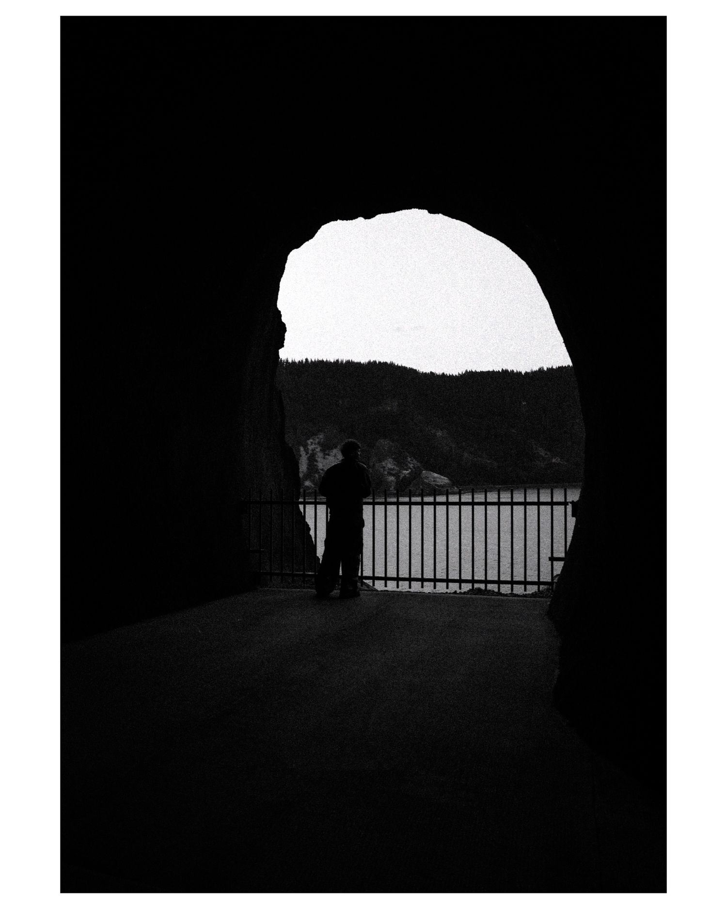 Dark tunnel view with railing silhouette against bright opening.