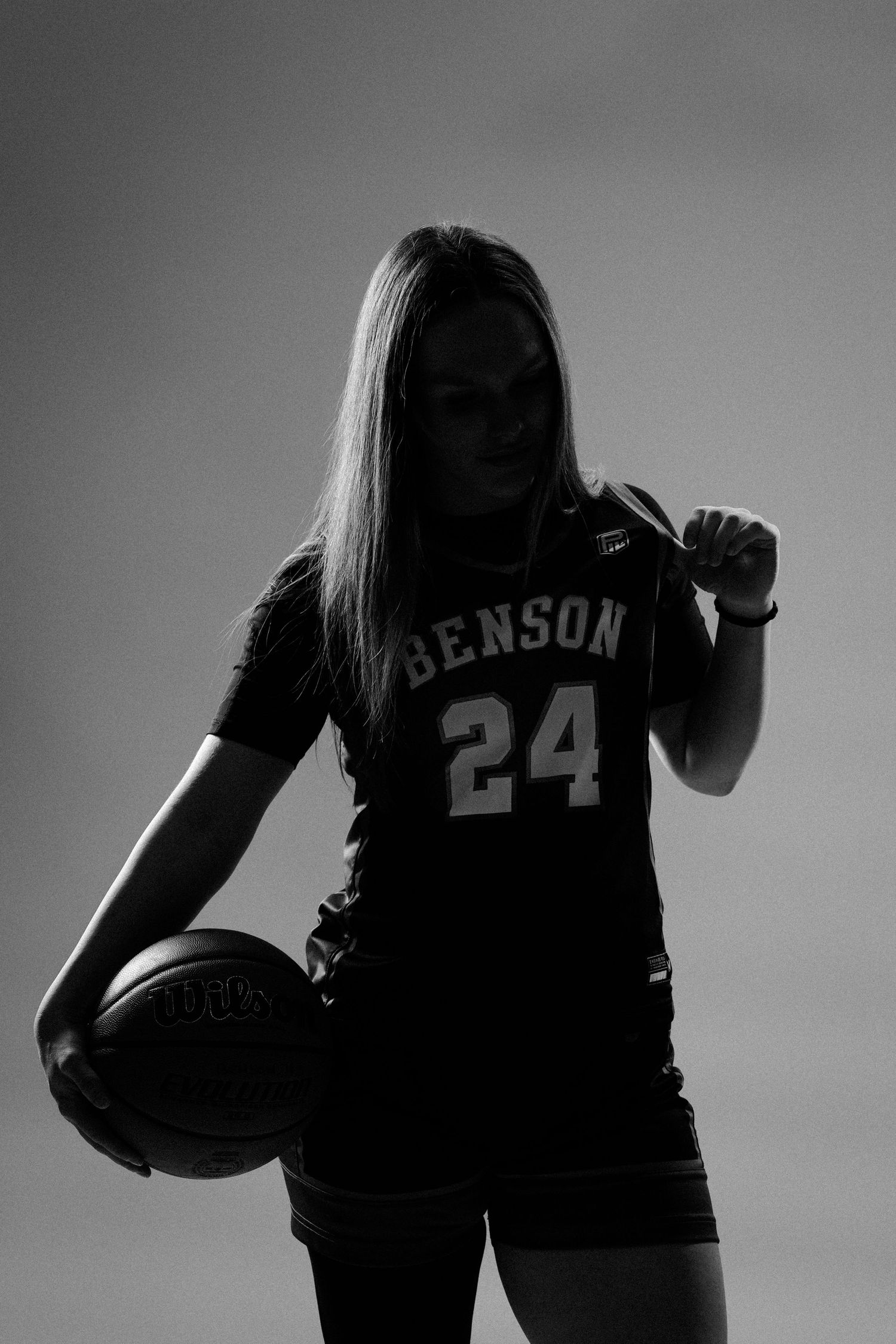 Silhouette series of basketball players in navy jerseys holding balls against gray background.