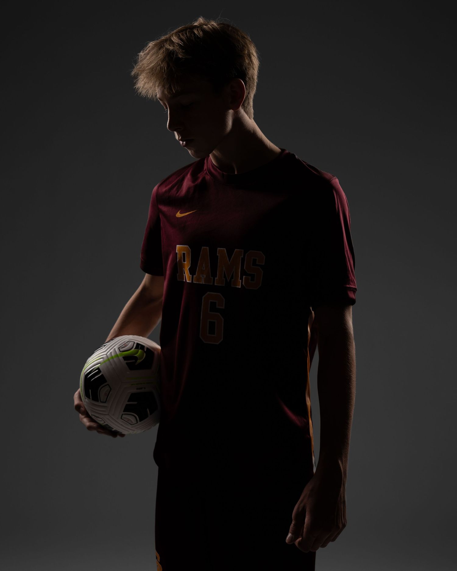 Dramatic silhouette portraits of athletes in dark jerseys against black background.