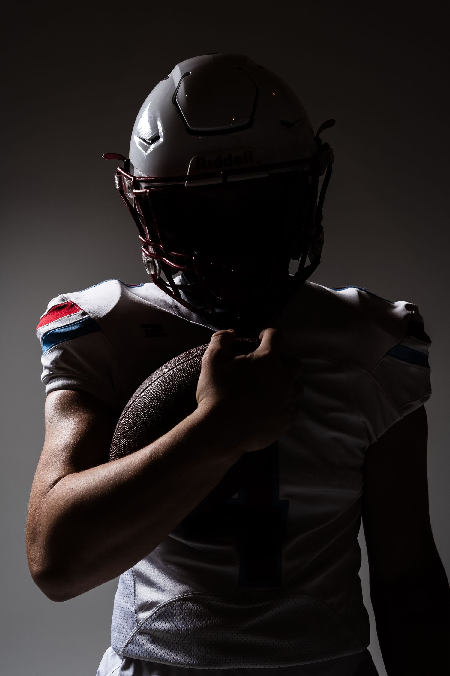 Dramatic silhouettes of football players in protective gear against dark background.