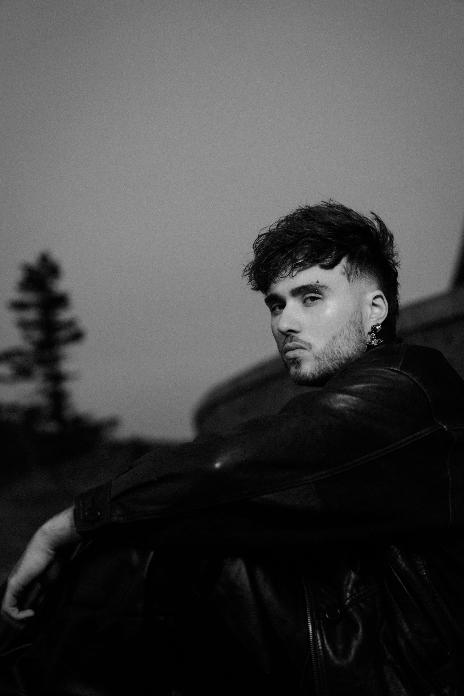 Moody black and white portrait against dark mountain landscape.