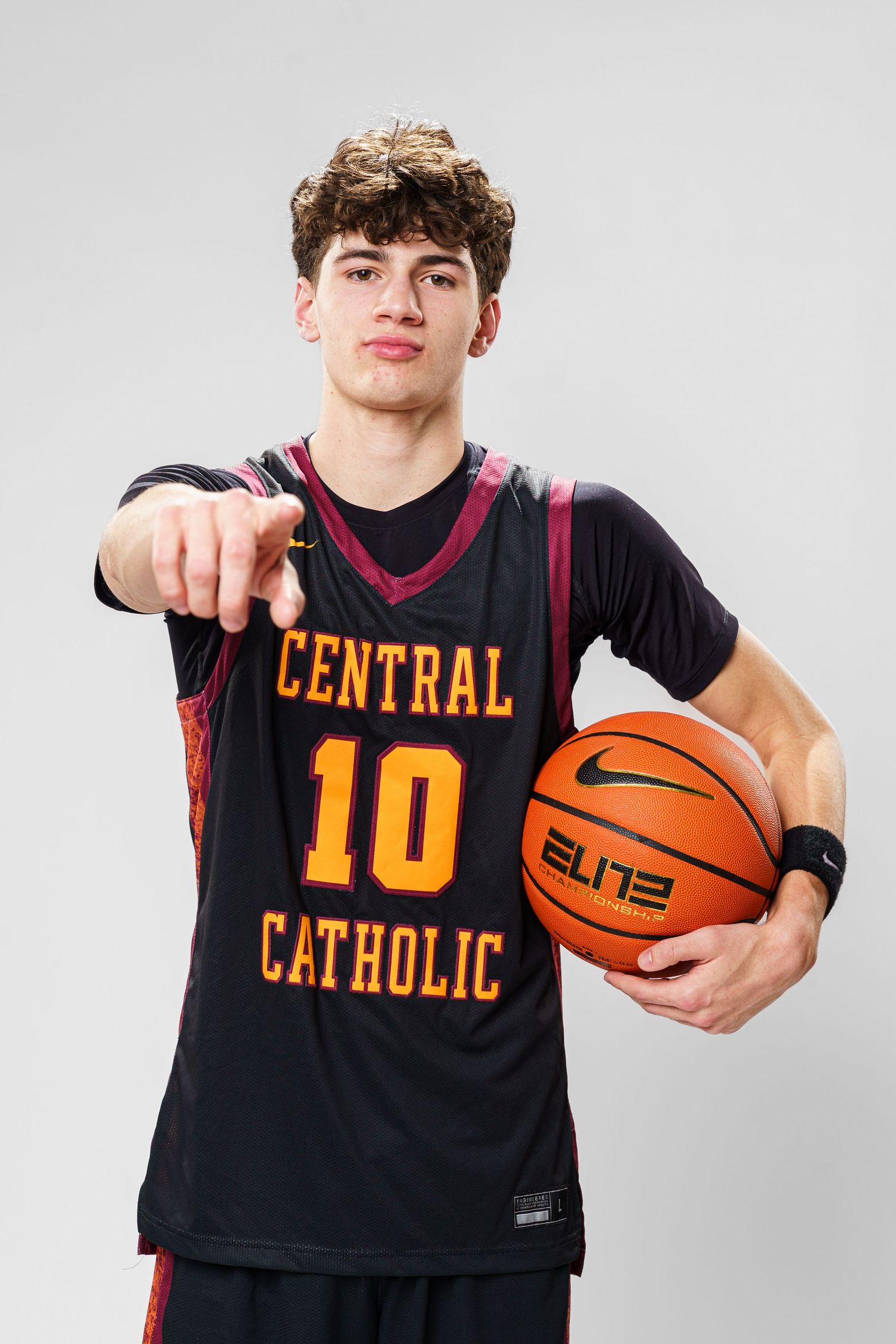Player in Central Catholic number 10 jersey points while holding basketball.