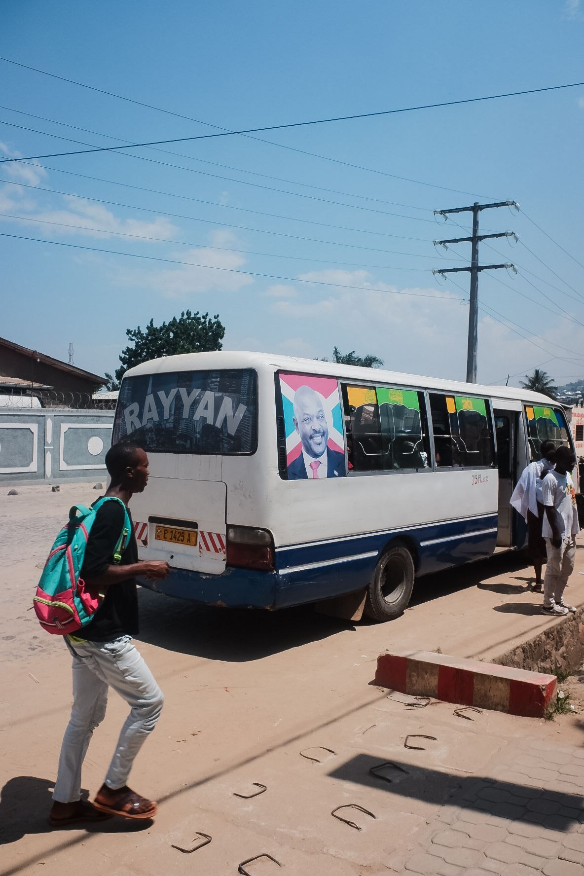 White buses parked along a dusty road under blue sky.