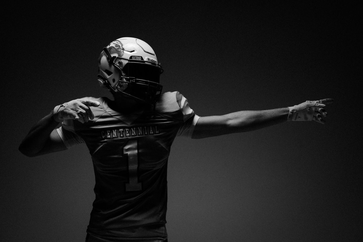 Dramatic silhouette of an athlete with outstretched arms against dark background.