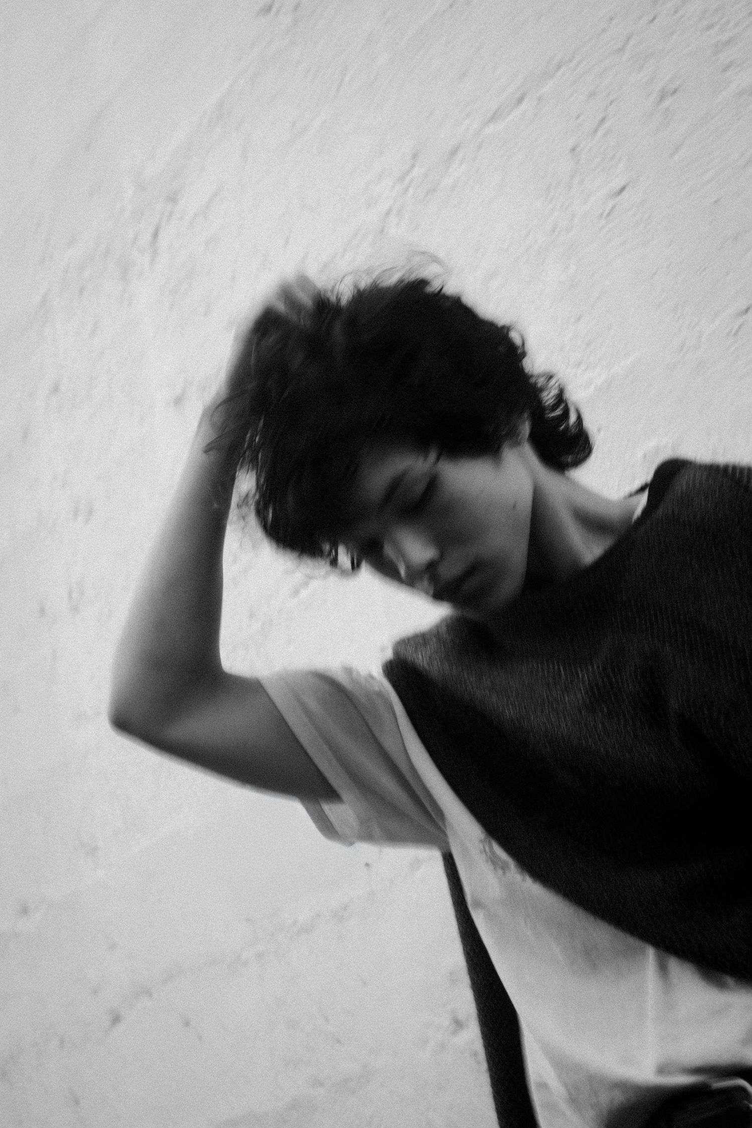 Motion blur sequence captures dynamic movement in black and white against textured wall.