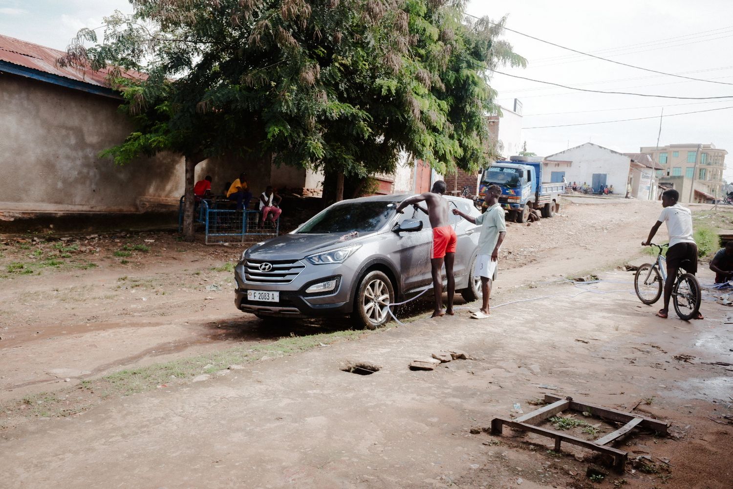 Dirt road with parked cars and bicycles in a residential neighborhood.